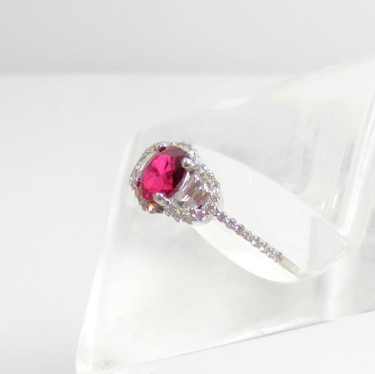 GIA analyzed oval ruby weighing exactly 1.17 cts and possessing absolute gem properties in terms of color and clarity, flanked by half moon cut diamonds of approximately .15 cts each.  There are another 44 diamonds in the setting all round and