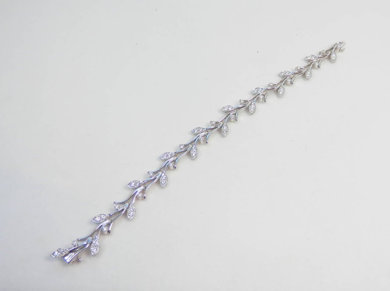 A vine/garland motif flexible 7 inch long bracelet by Tiffany & Co.  It is 18K white gold and platinum with 54 well cut and well matched white diamonds.