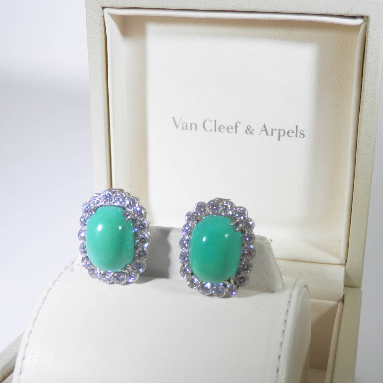 Turquoise and diamond earrings by VC&A and numbered 28711.  These are vertical cushion shaped ear clips centering a high cabochon of turquoise bordered by 3.6 cts of excellent white diamonds in platinum settings.  The ear clips are signed on the