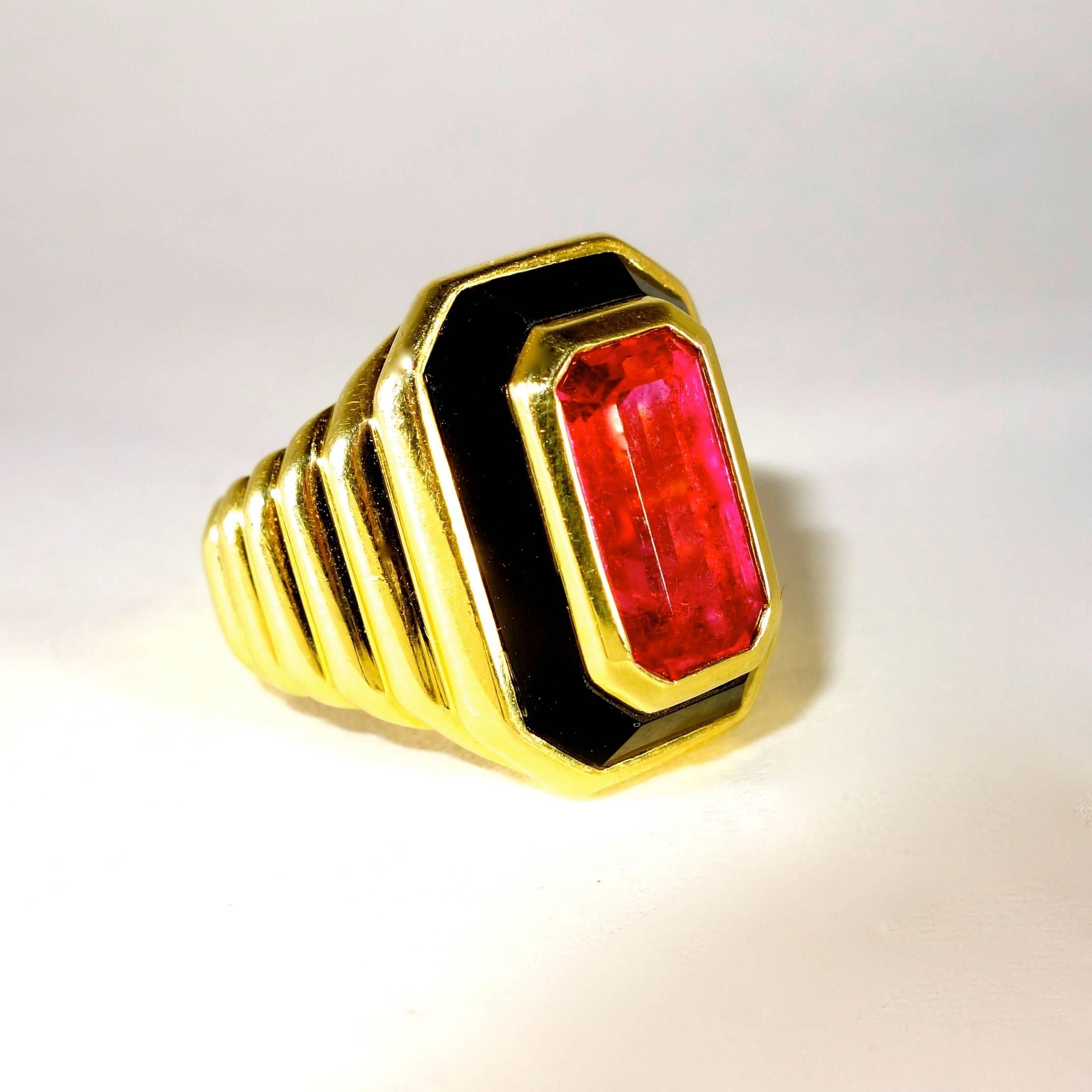 Bright vivid pink tourmaline, approximately 4-5 cts, emerald cut, framed by fancy cut onyx.  18K yellow gold ring now a size six and we can size easily.  Inside of the shank has a hallmark in a lozenge.