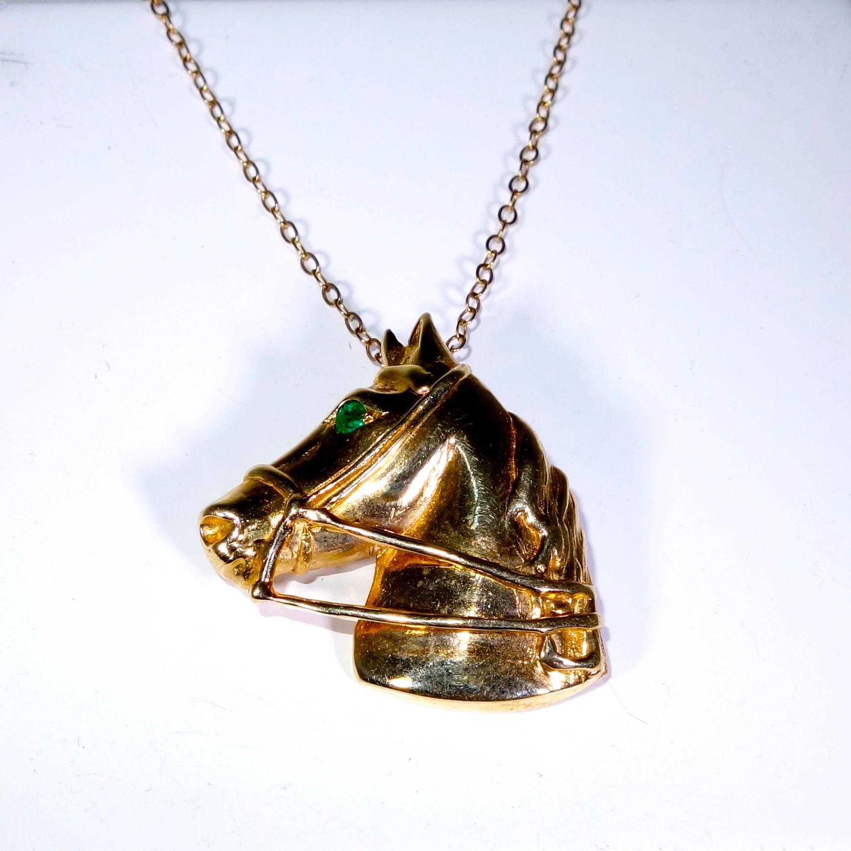 14K yellow gold with bright green emerald eyes, which weigh approximately .20 cts. this horse is 1 inch in diameter and suspends from a gold chain.