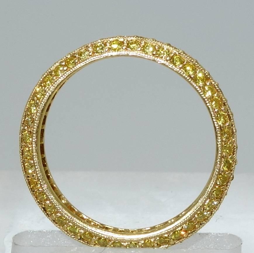 Three rows of fine natural fancy intense yellow diamonds are set in this hand made 18K yellow gold eternity band.  The diamonds are chosen to match well in cut, color and clarity thus creating a bright colorful statement on the finger.  This band is