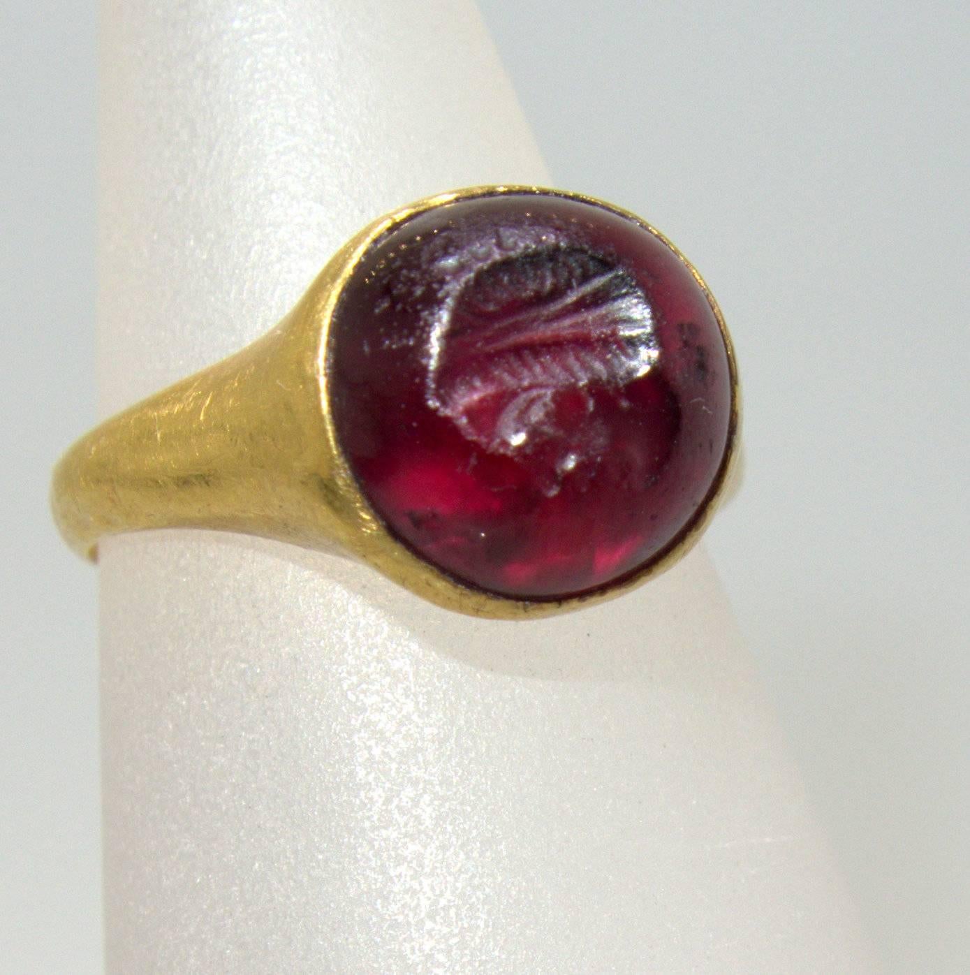 Roman, 1st century, this ring which is a very high content of gold (22k), holds a intaglio ruby of a head or mask.  Accompanying this superb example of ancient jewelry in fine condition is a document describing and dating the piece from an expert in