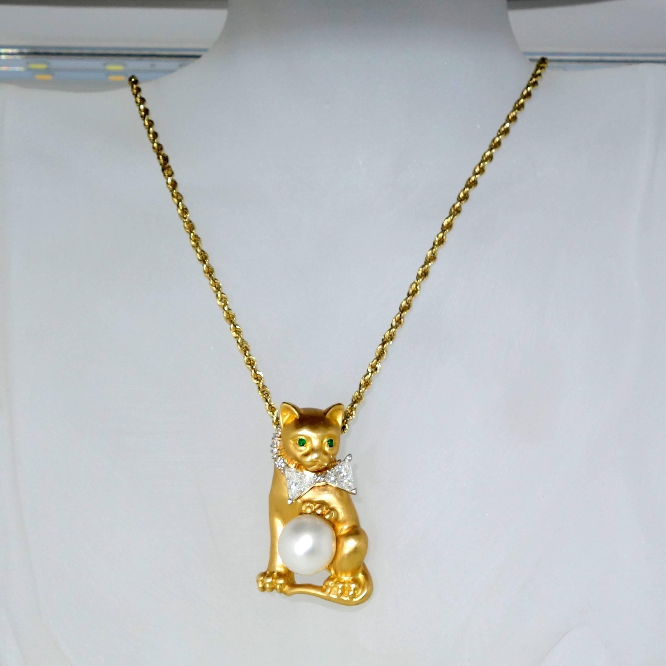 18K and platinum finely modelled cat playing with a ball which is a fine South Sea pearl, measuring 11 mm.  The kitty cat( an inch and one half in length) sports a platinum diamond bow tie of two well matched triangular cut diamonds.  These fine