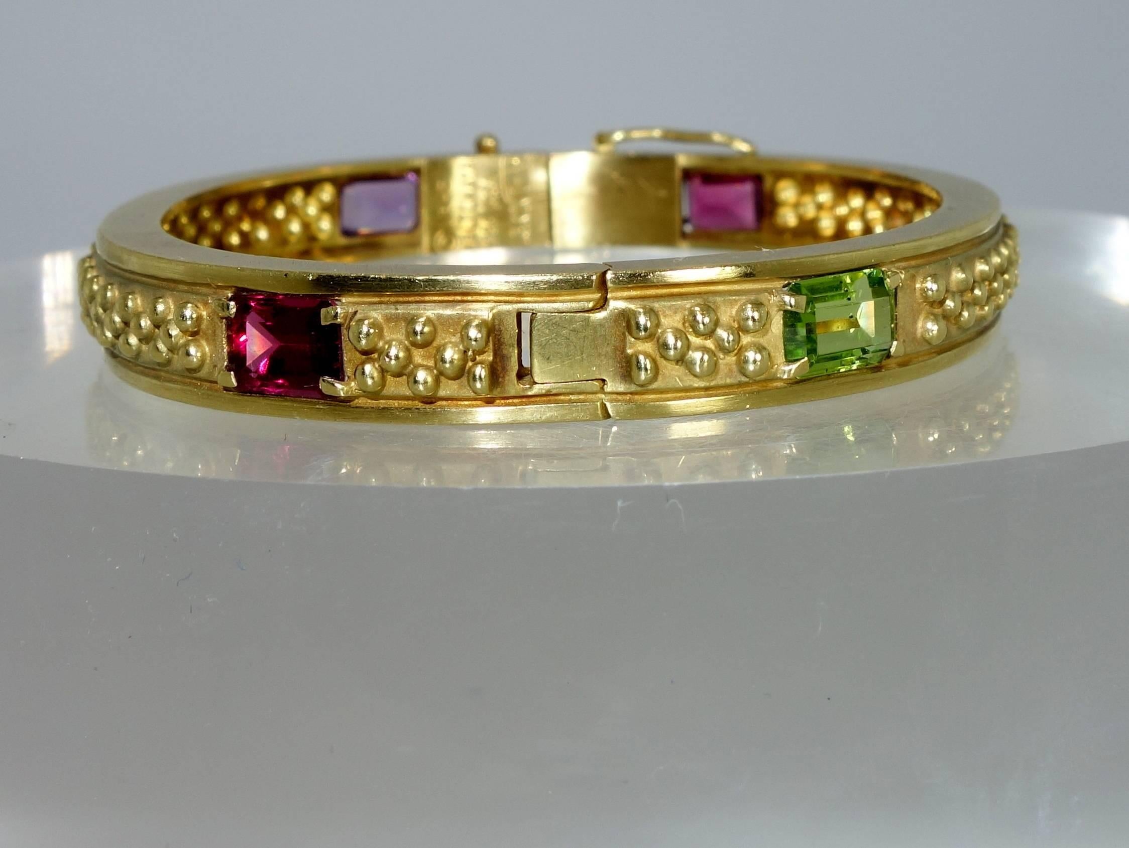 18K yellow gold with 6 rectangular cut stones: pink and green tourmaline, garnet, amethyst and peridot all come together to create a colorful statement for the wrist.  This piece weighs 31.6 grams. This piece is a good size and will fit most wrists.