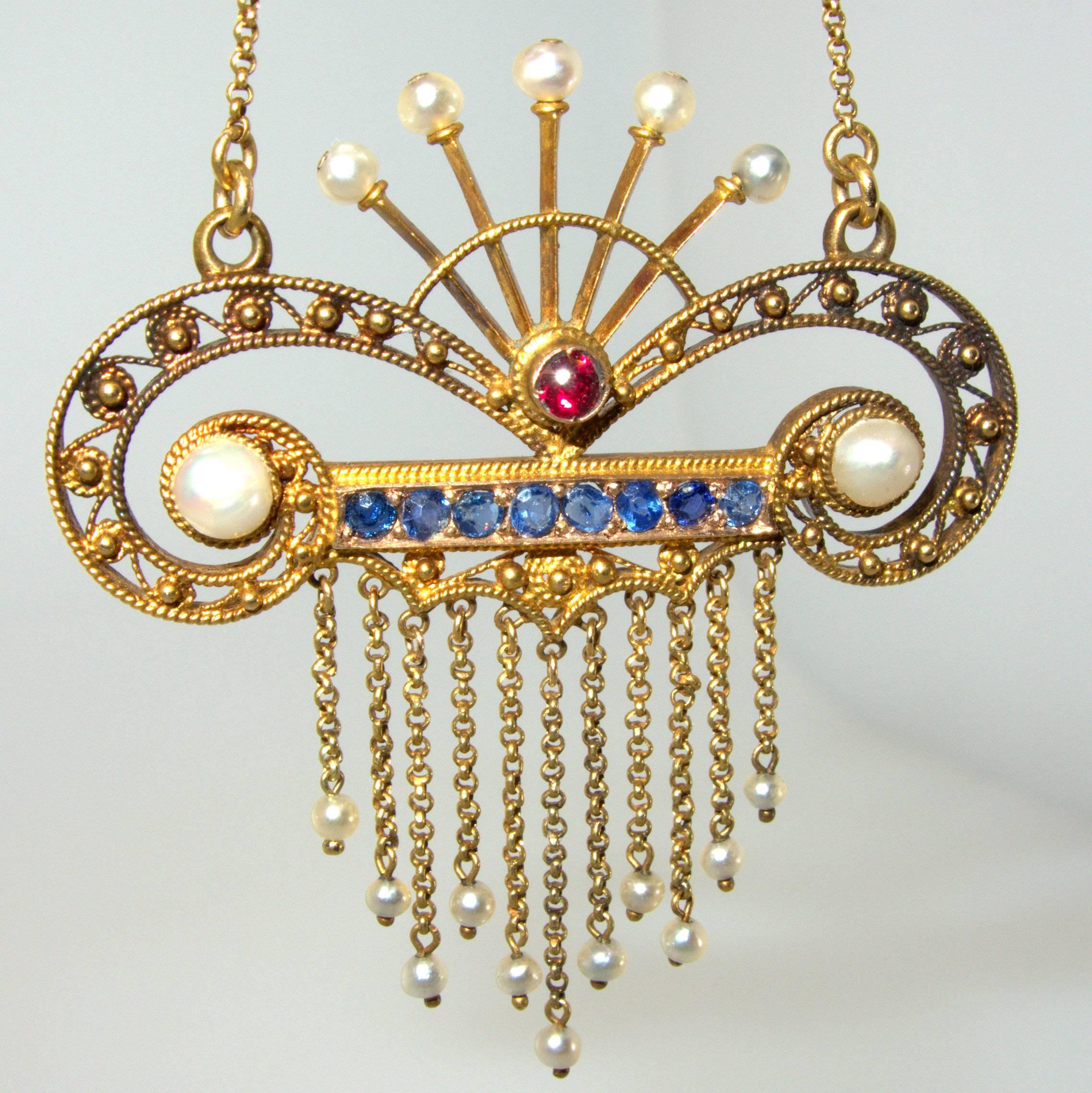 Circa 1900, with natural seed pearls, Ceylon sapphires and centering a ruby, this unusual pendant is two inches long and suspends from a 16 inch chain making the necklace 18 inches long.