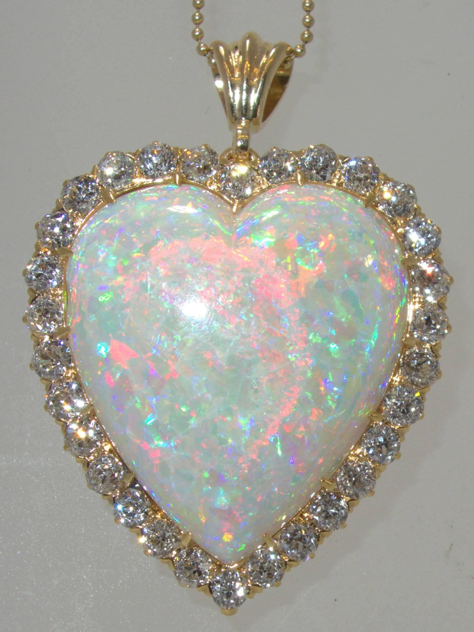 The large heart shaped Australian opal possesses all three desired colors: green, blue and red.  This opal which is in fine condition with no crazing weighs approximately 30 cts.  It is surrounded by 30 white and clean round diamonds weighing