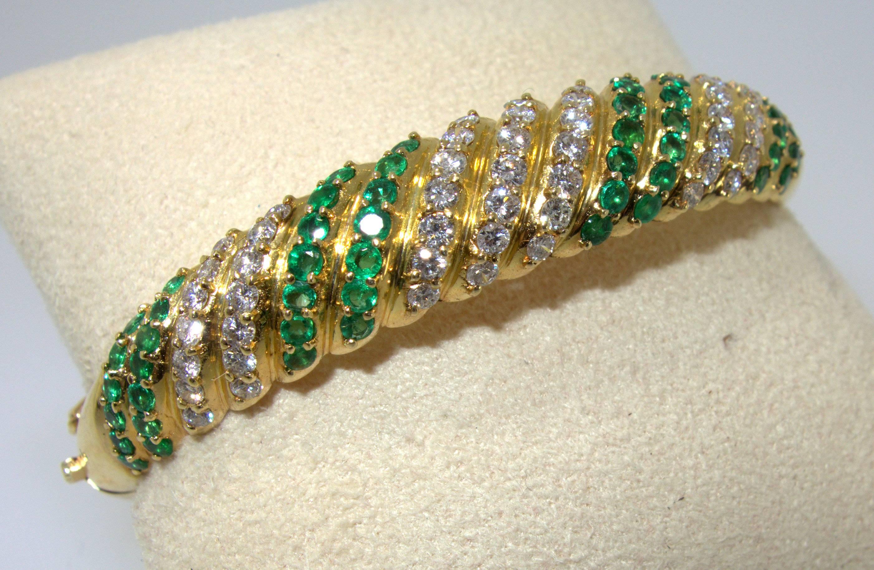 Bright green emeralds and white diamonds are set into this lovely gold bangle bracelet.  The size is medium and will fit almost all wrists. The interior circumferences is approximately 7 inches.  The 49 diamonds are all well matched, white (H/I),