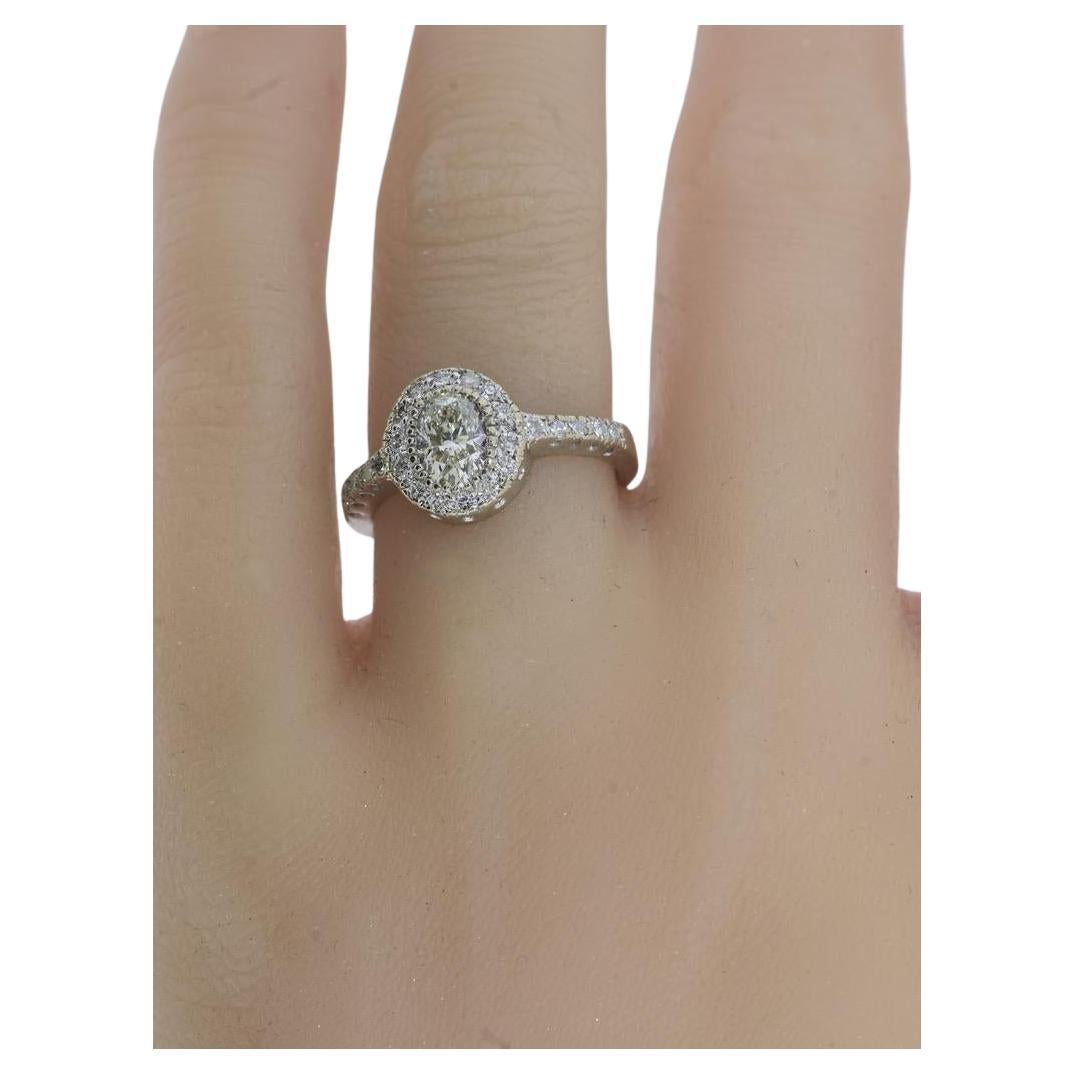 Ovaler Diamantring aus 18k Gold. Der Mittelstein, ein Diamant im Ovalschliff, wiegt 0,66 Karat. Er wird auf J/K (nahezu farblos bis zu einer leichten Tönung) und sehr leicht eingeschlossen (VS1) geschätzt. Der Diamant ist von kleineren, passenden