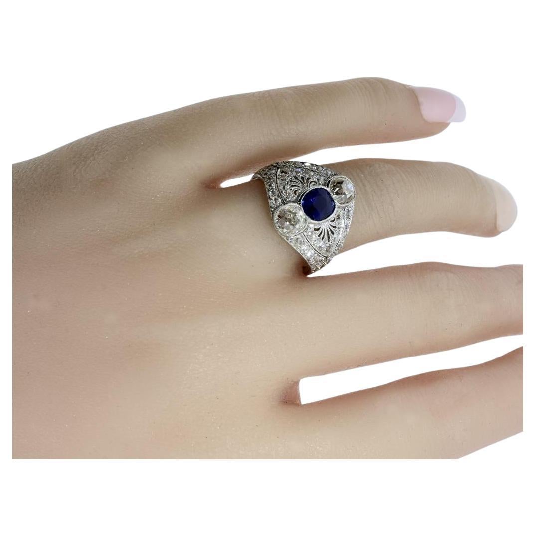 Edwardian platinum ring by Marcus & Co., crafted in 1915 in the United States. The ring features a central cushion-cut vivid bright blue and clean sapphire estimated to weigh .85 carats, and surrounded by 44 old European cut diamonds estimated to