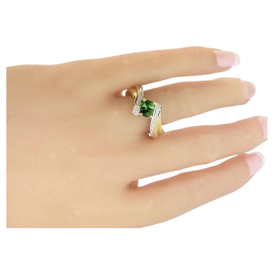 18K yellow and white gold vintage ring centering a vibrant green natural Tsavorite.  This stone is so bright because of its clear even color.  It is estimated to weigh approximately .90 cts.  Accenting this fine center stone are 16 brilliant cut