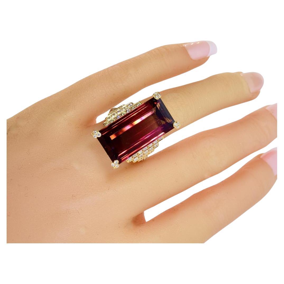 Fine natural Rubellite, also called red tourmaline. This stone is bright, clear and displays a vivid and deep raspberry color. This very long emerald cut stone is held by four prongs each set with 3 white brilliant cut small diamonds. The stone
