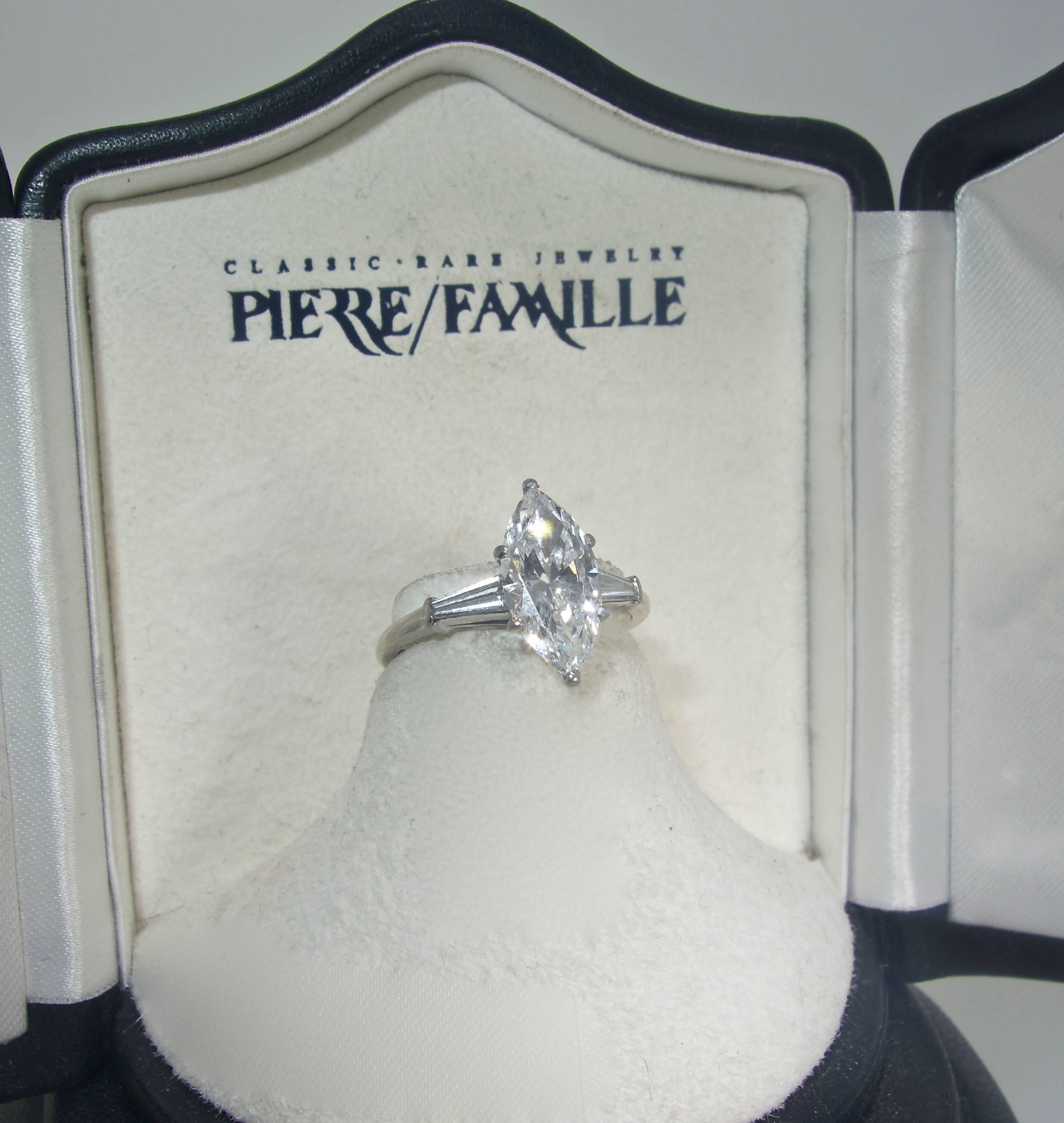 Accompanied by a certificate from the Gemological Institute of America stating that the 2.32 ct. marquis diamond is D (colorless) and VVS2 (very very slightly included to the second degree), this three stone platinum ring is a classic example from