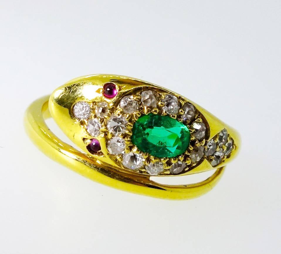 This charming 18K snake ring possesses an approximately .33 ct. bright green Colombian emerald surrounded by old cut diamonds.  There are approximately .50 cts. of diamonds.  The smiling snake has ruby eyes.  This snake motif was very popular in