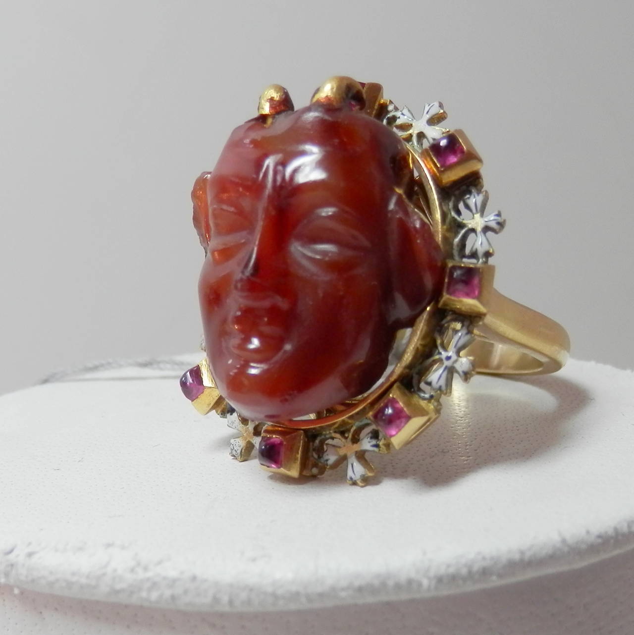 The center carving in agate is a 3 dimensional devil figure.  This carving is c. 1550.  It is set in an antique Holbeinesque ruby and enamel frame.  This frame dates to the mid-19th century.  The ring has been reinforced by adding a new gold shank.