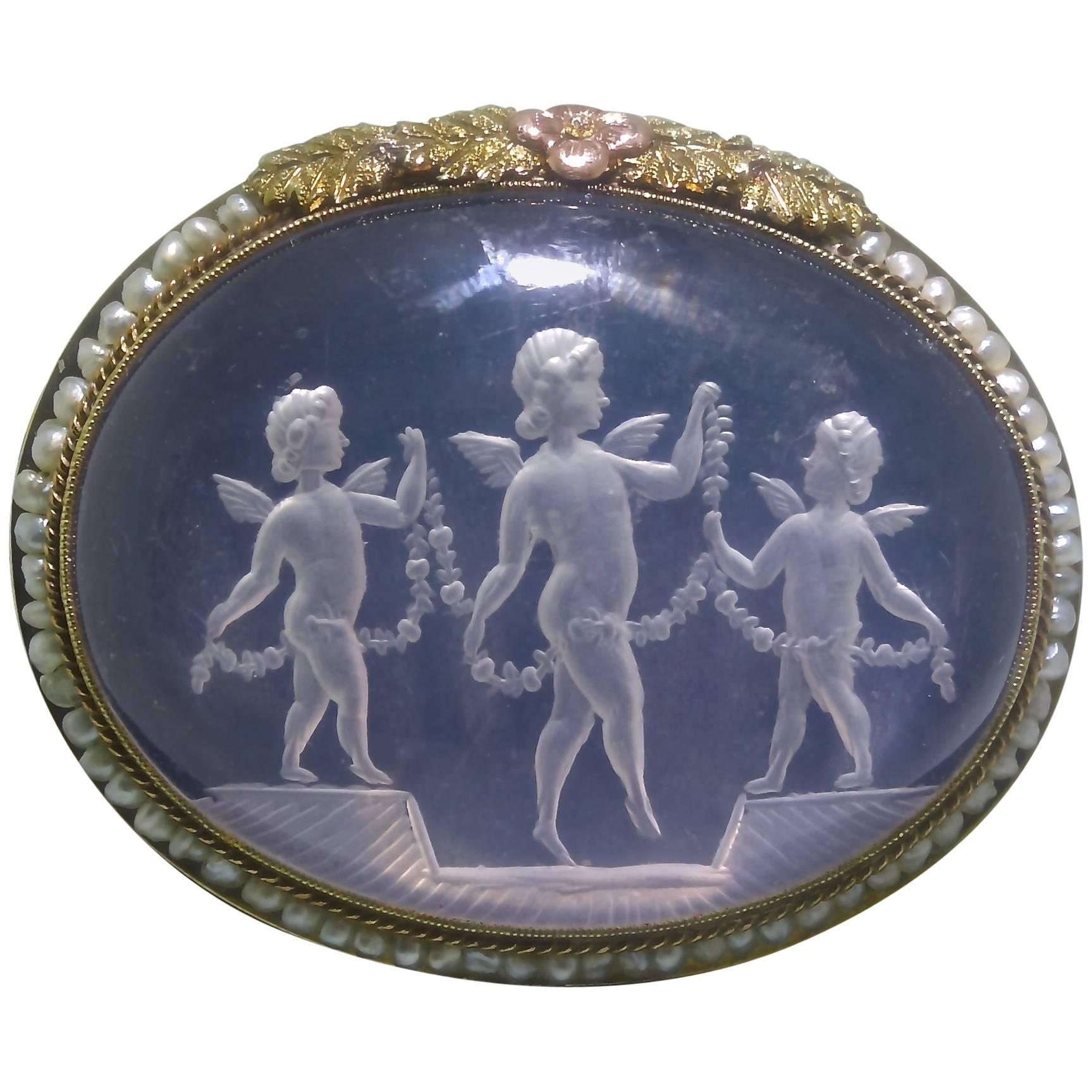Antique  gold brooch with a charming motif of cherubs finely carved in rose quartz and encircled with natural seed pearls and multicolored gold.  Intaglios such as this charming one is usually done in rock crystal so this example is unusual.  The