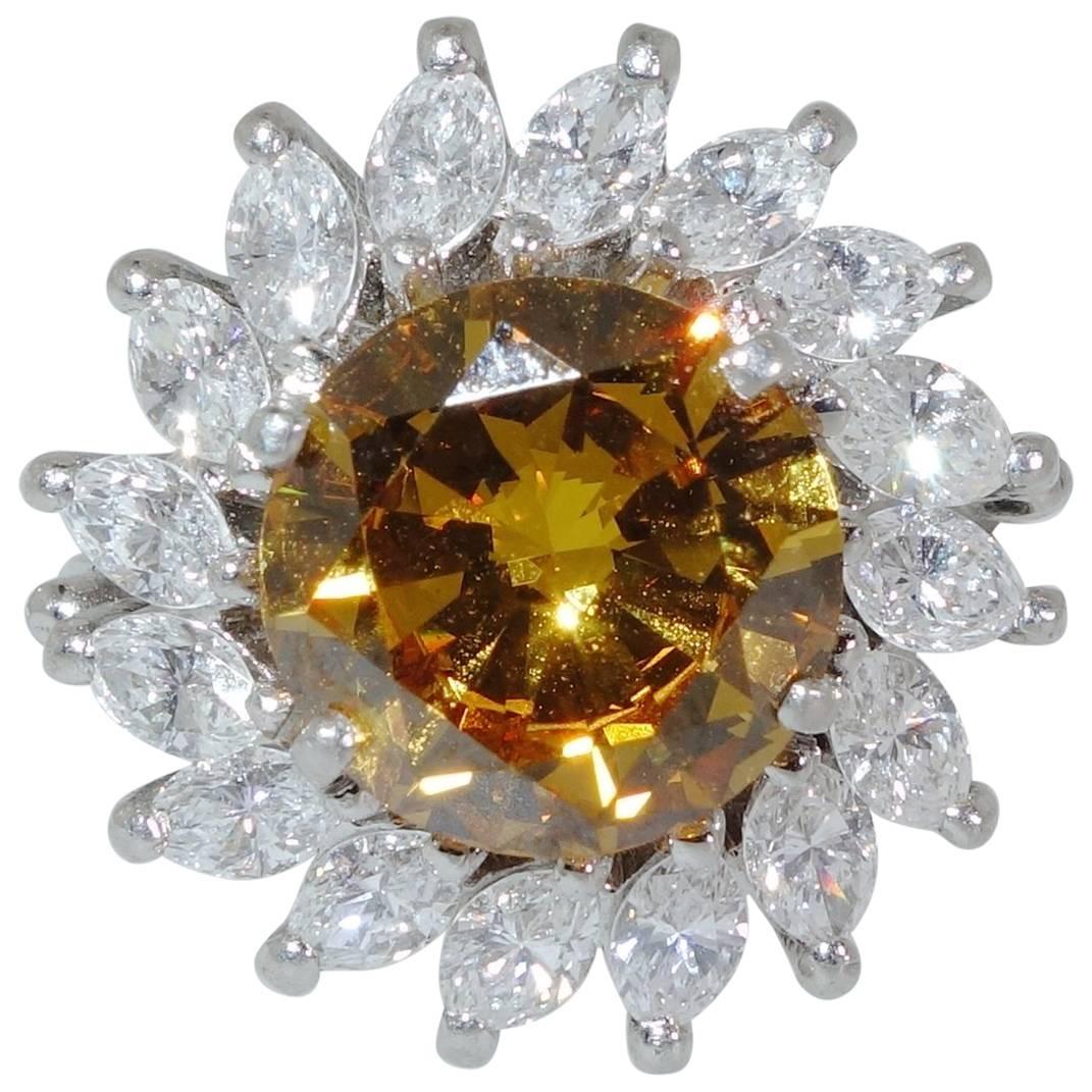 Diamond of a brilliant cognac (golden brown) color weighing 2.68 cts. This diamond has been examined by the G.I.A. (Report No. 2430550), and has treated color.  The white marquis cut diamonds surrounding this stone weigh approximately 1.6 cts.  They
