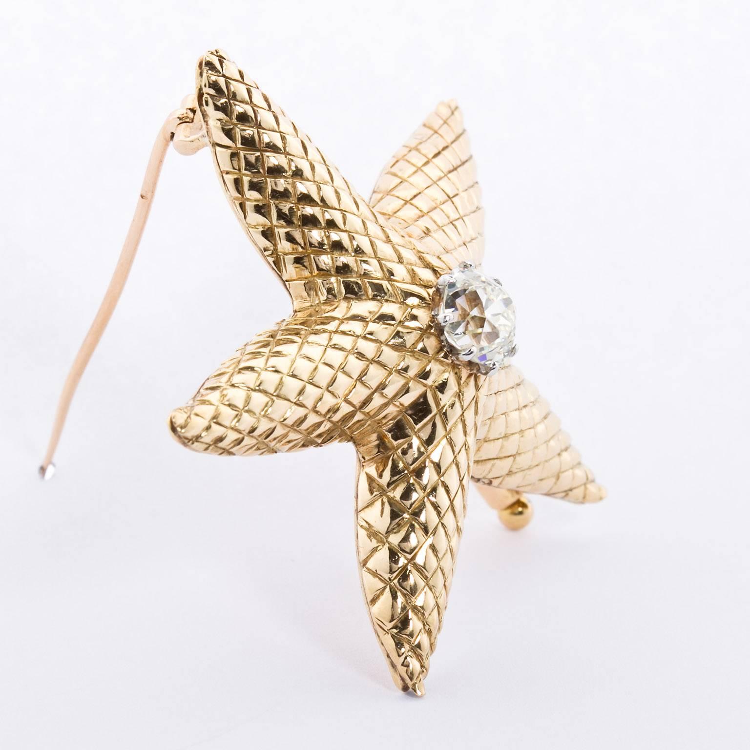 A stylized scale pattern starfish brooch of yellow gold with an approximately 1.77 carat I color VS clarity old miner cut center diamond. Inscribed 