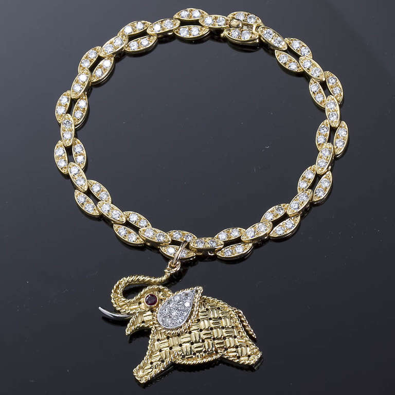 Van Cleef & Arpels 18k gold link charm bracelet set with 90 diamonds weighing approximately 3 cts and suspending a basket weave good luck elephant with 10 diamonds set in the ear and a ruby eye. Both pieces are signed and stock numbers are present