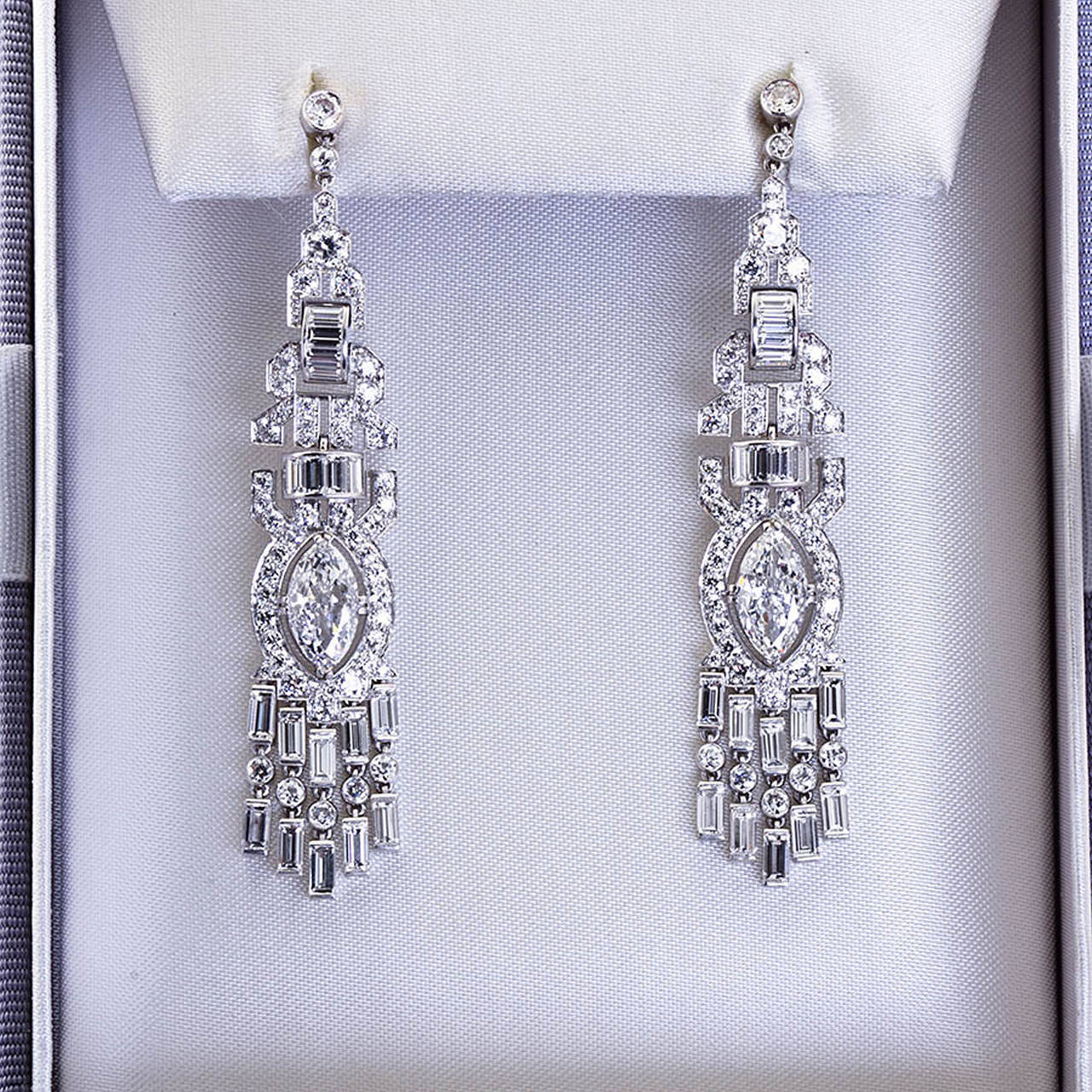 A magnificent pair of diamond in platinum dangle chandelier style earrings contain two large marquise shaped center diamonds with round brilliant and baguette shaped diamonds throughout. Art Deco Period.
Diamond weights: 2 Marquise shapes 1.01 ct. E