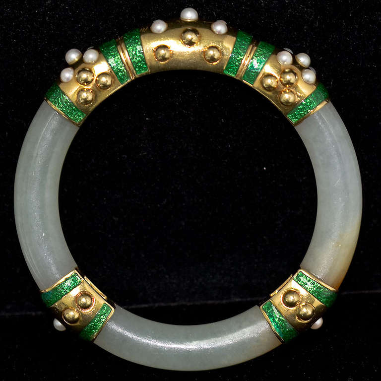 An original carved jade bangle with 18k yellow gold, green enamel and pearl accents. Bangle is11mm thick, inner dimensions are 2-1/2