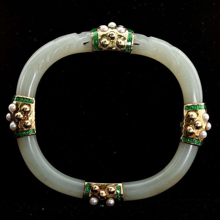 An original carved jade bangle with 18k yellow gold, green enamel and pearl accents. Bangle is 8mm thick, inner dimensions are 2-1/2