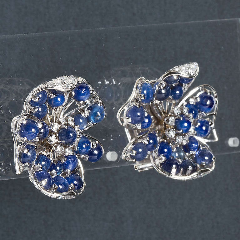 A pair of 18k white gold diamond and cabochon sapphire ear-clips approx. 19.00 ctw of blue sapphires and 0.75 ctw diamonds. 1 1/8 inches wide. Circa 1960s.

No. 5660