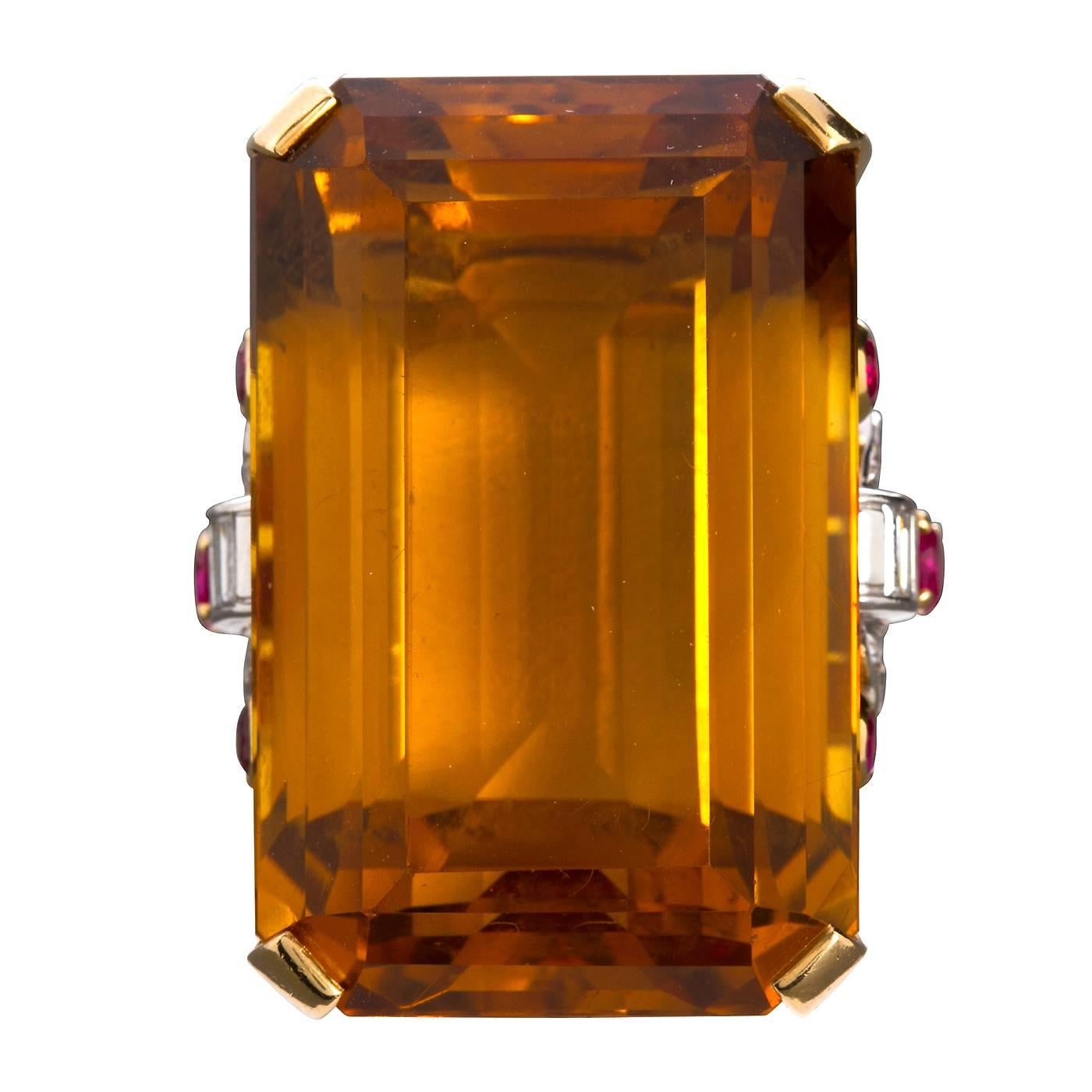 A large approximate 75 carat rectangular step cut citrine mounted in a Retro styled 14 karat yellow and white gold.  Ring gallery set with round brilliant red rubies and baguette diamonds.

Ring sized to fit.

Gem Dimensions: 1-1/2 x 7/8" inch