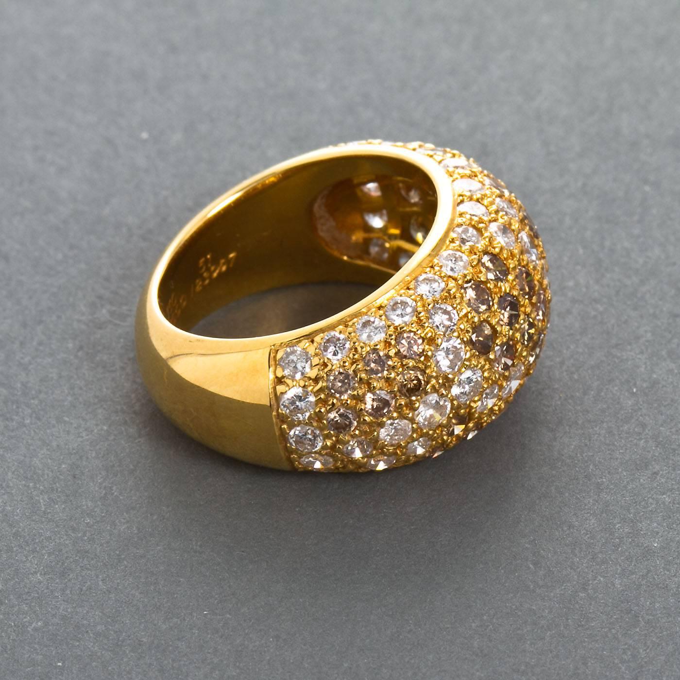 An 18 karat gold 'boule' (bombé) ring by Cartier Paris from the Sauvage collection. Signed and numbered by Cartier, with french assay and workshop marks.  Pave brown and white diamonds approximately halfway set around the band, mounted in 18k