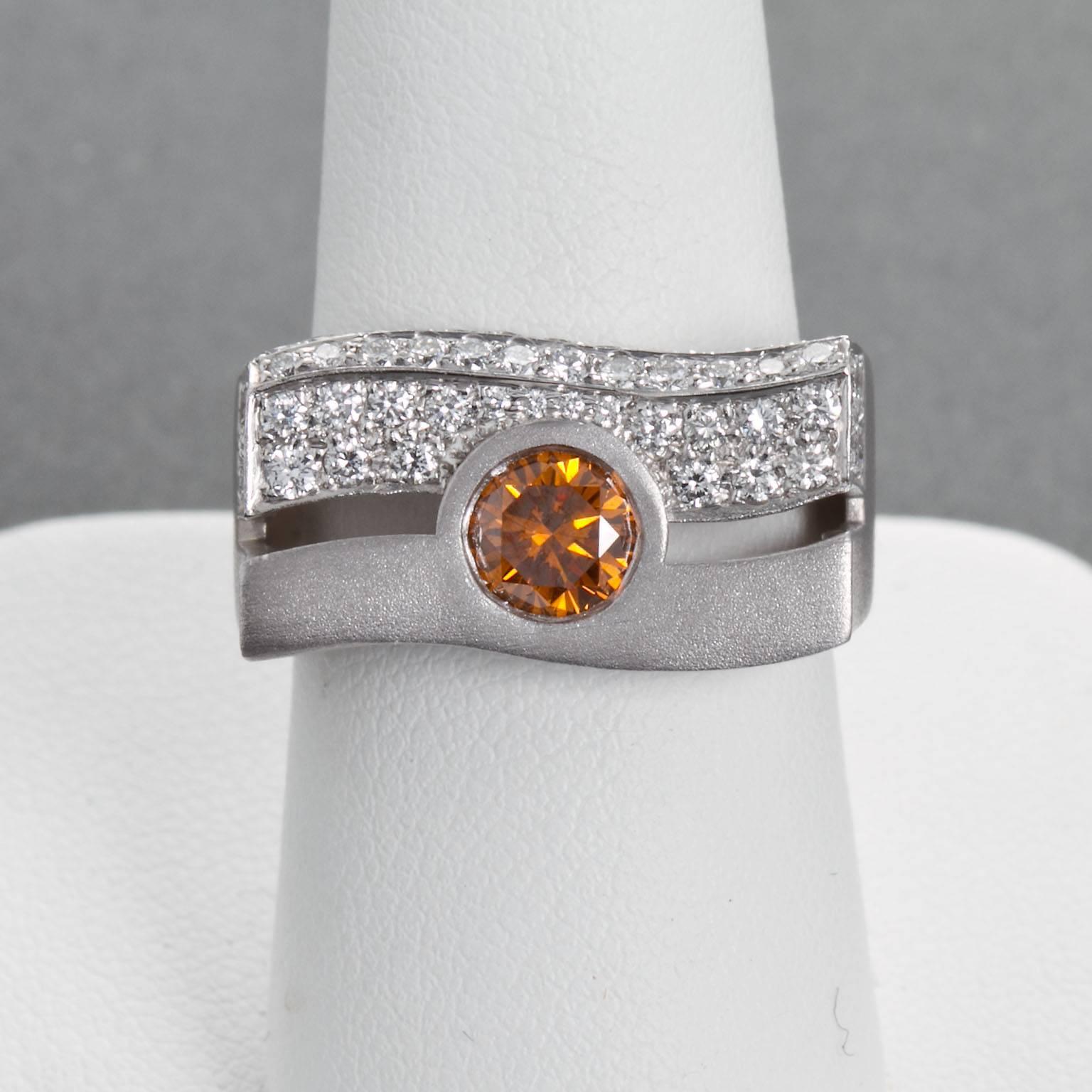 A round brilliant cut fancy deep yellowish orange diamond set in a white gold modern wave style ring with one side being diamond pavé.

Center diamond is approx. 0.60 carat. Accompanied by GIA Colored Diamond Report.  Clarity is SI2.

Ring