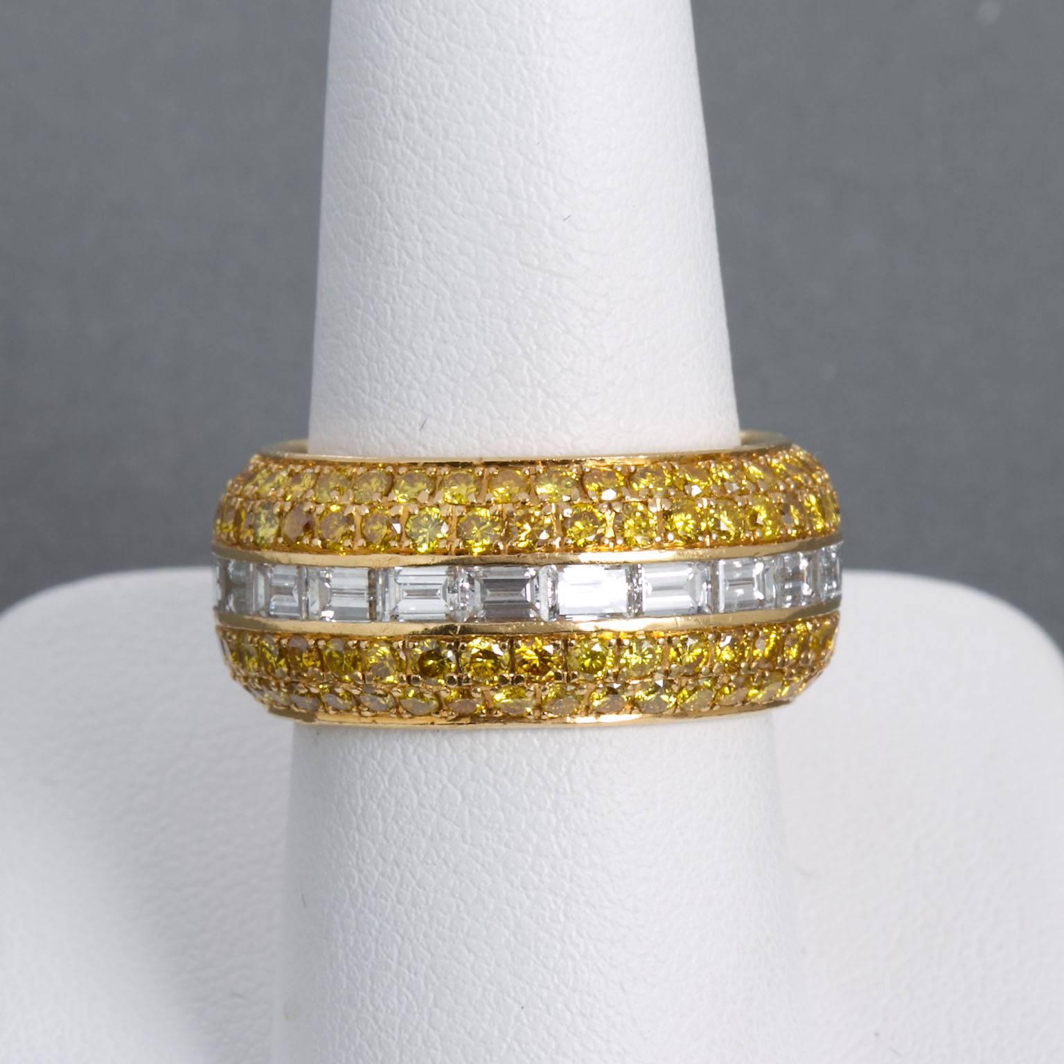 A wide fancy yellow and white diamond in 18 karat yellow gold band.  Set with 2.90 ctw of pavé set vivid yellow round brilliant cut diamonds and 2.90 ctw of channel set baguette cut white diamonds. Signed and hallmarked by Alan Friedman of Beverly