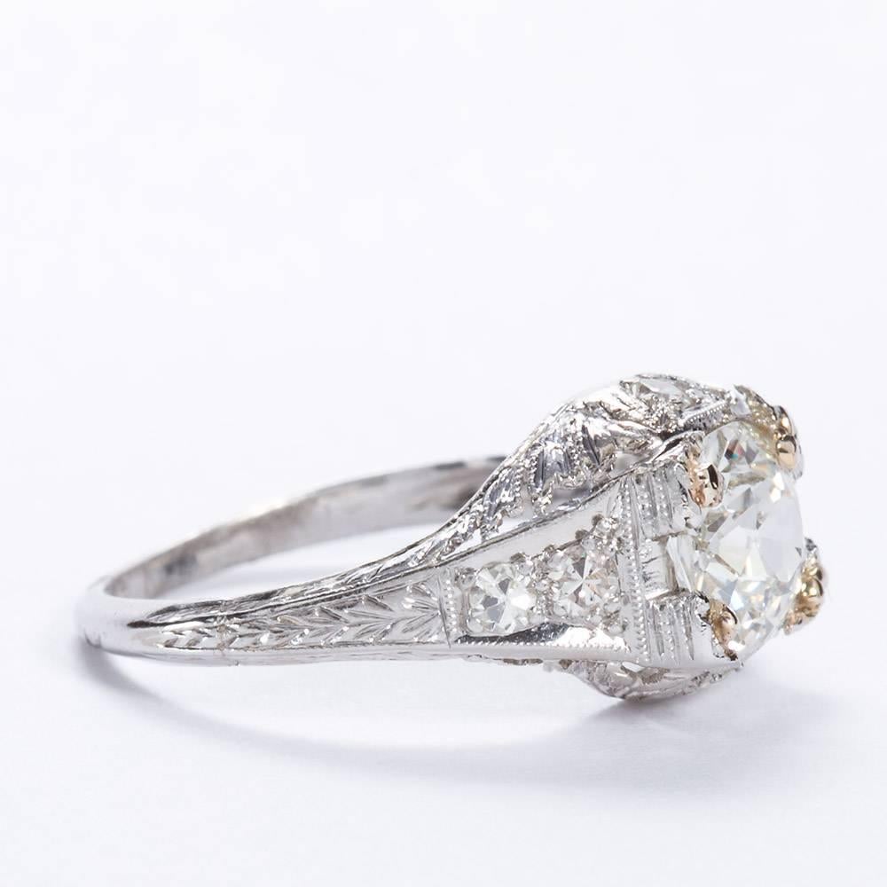 A 1920s stylized ring with millegraining and antique style etching of platinum set with one Old Mine cut diamond of 1.08 ct J color, VS1 clarity.  Center stone prongs are 14 karat gold.  Ring shoulders are set with four round cut diamonds 0.30