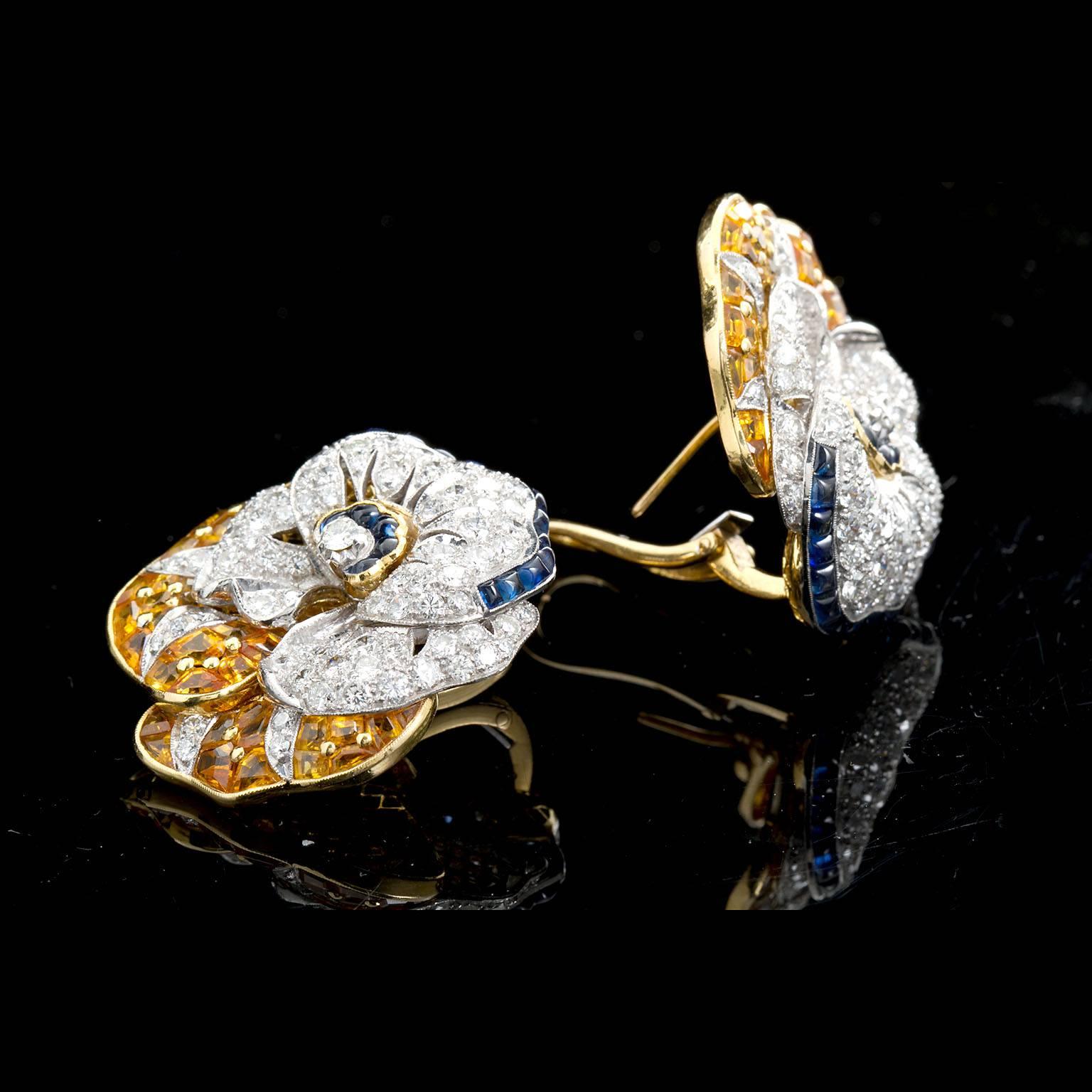 A pair of the famous pansy style earrings by Oscar Heyman. Set with round brilliant cut diamonds, sugarloaf style calibrated blue sapphires and calibrated step-cut faceted yellow sapphires in a hand crafted and stylized 18 karat yellow and white