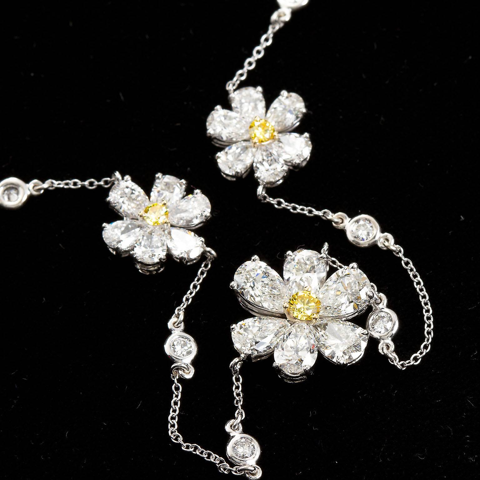A wonderful diamond pendant necklace with an 18 inch diamond in white gold chain. Center floret contains approx. 3.00 ctw of pear shape diamonds with a center fancy intense yellow round diamond of 0.15 cts. The two smaller florets are each approx.