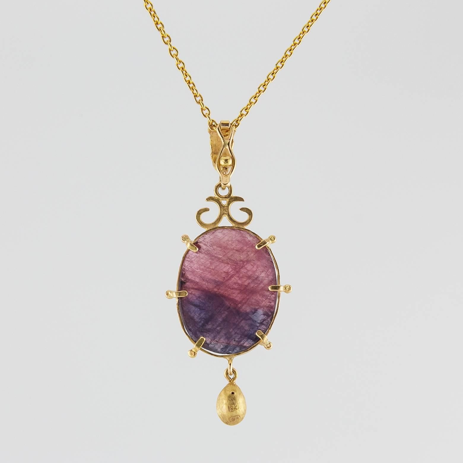 Irregular Shaped Purple Maroon Sapphire Pendant. This exquisite piece is a stunner. It has different shades of purples in a unique setting that lets the imagine run wild- off into the sunset. 18K Yellow Gold hammered with excellence adds to the