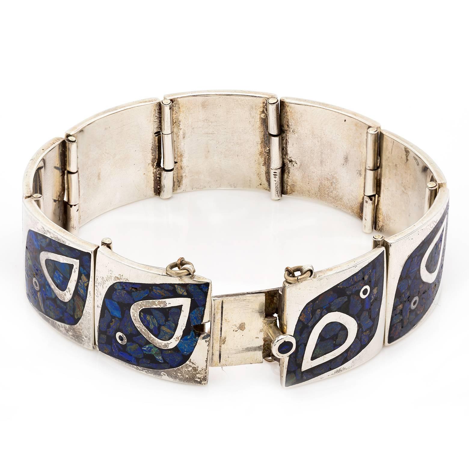 This handmade sterling silver bracelet is an antique from the 1970's with inlaid lapis stones, turquoise, and other complimenting blue stones. Stamped with the designers emblem this one of a kind bracelet also has a matching necklace, please inquire.