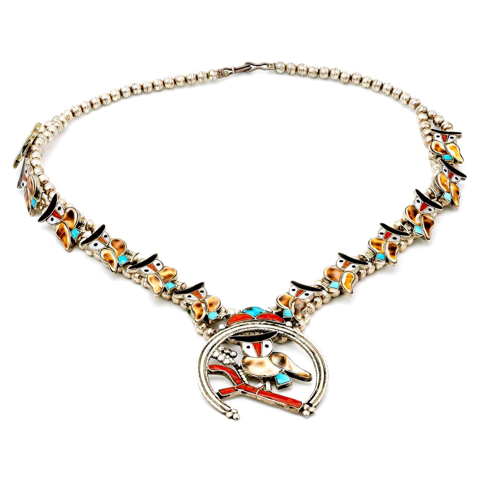 Diese handgefertigte Halskette im Stil einer Kürbisblüte ist mit Perlmutt, Türkisen, Korallen und Muscheln besetzt. Ein tolles Sammlerstück für Zuni-Schmuck und Eulenliebhaber. 