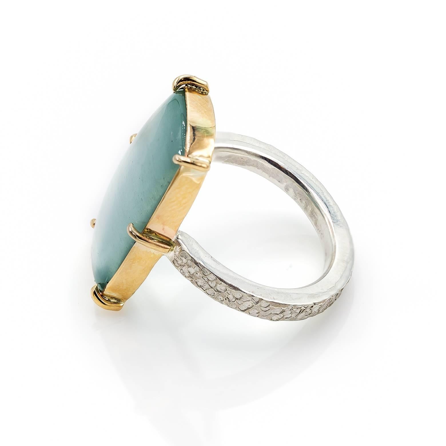 This two-toned ring is a beautiful statement ring made with a rare Cats Eye Aquamarine center stone in a slightly rounded rectangle shape. The 14K yellow gold bezel beautifully embellish the aquamarine and the band is a light white sterling silver