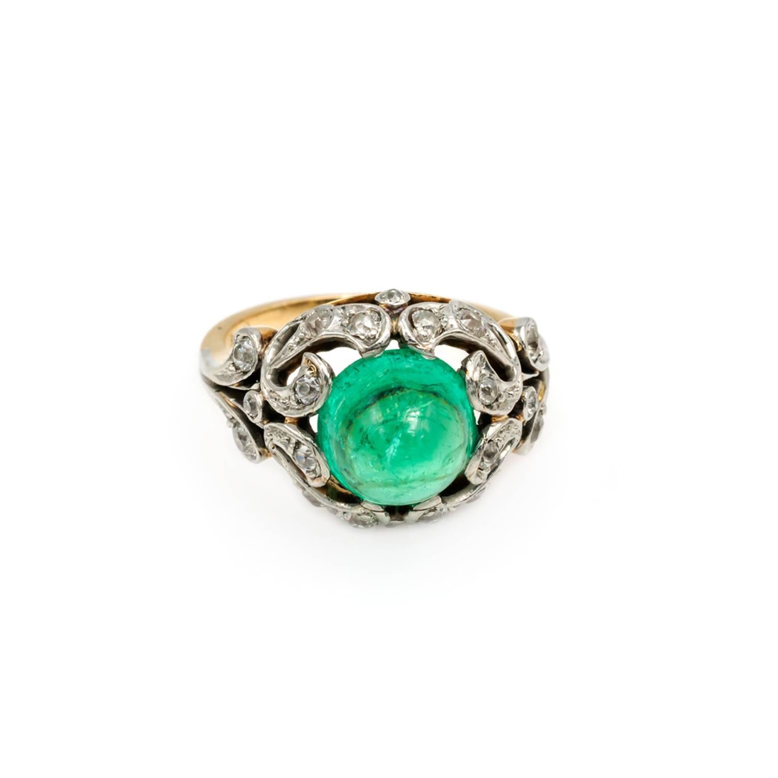 This stunning antique Edwardian ring is decorated with diamonds in a filigree fashion around the central mint green emerald cabochon. The old mine cut diamonds are set in platinum and the band is a rosy 14K yellow gold. Approximately 3 carats of