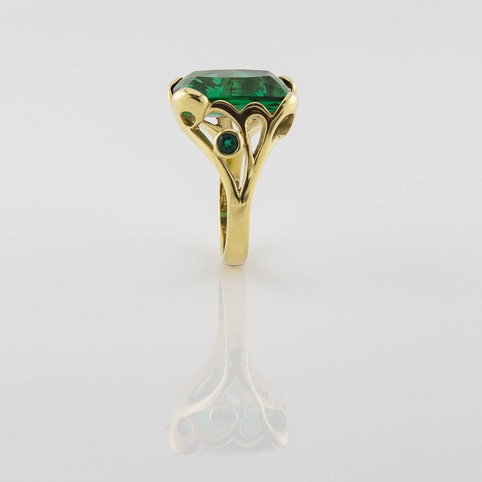 This deep green emerald-cut tourmaline ring is absolutely divine. The unique free form bezel shows artistic class and is decorated with 2 small green tourmalines on the side. The perfection of this stone gives it added glamour and  insatiable taste.
