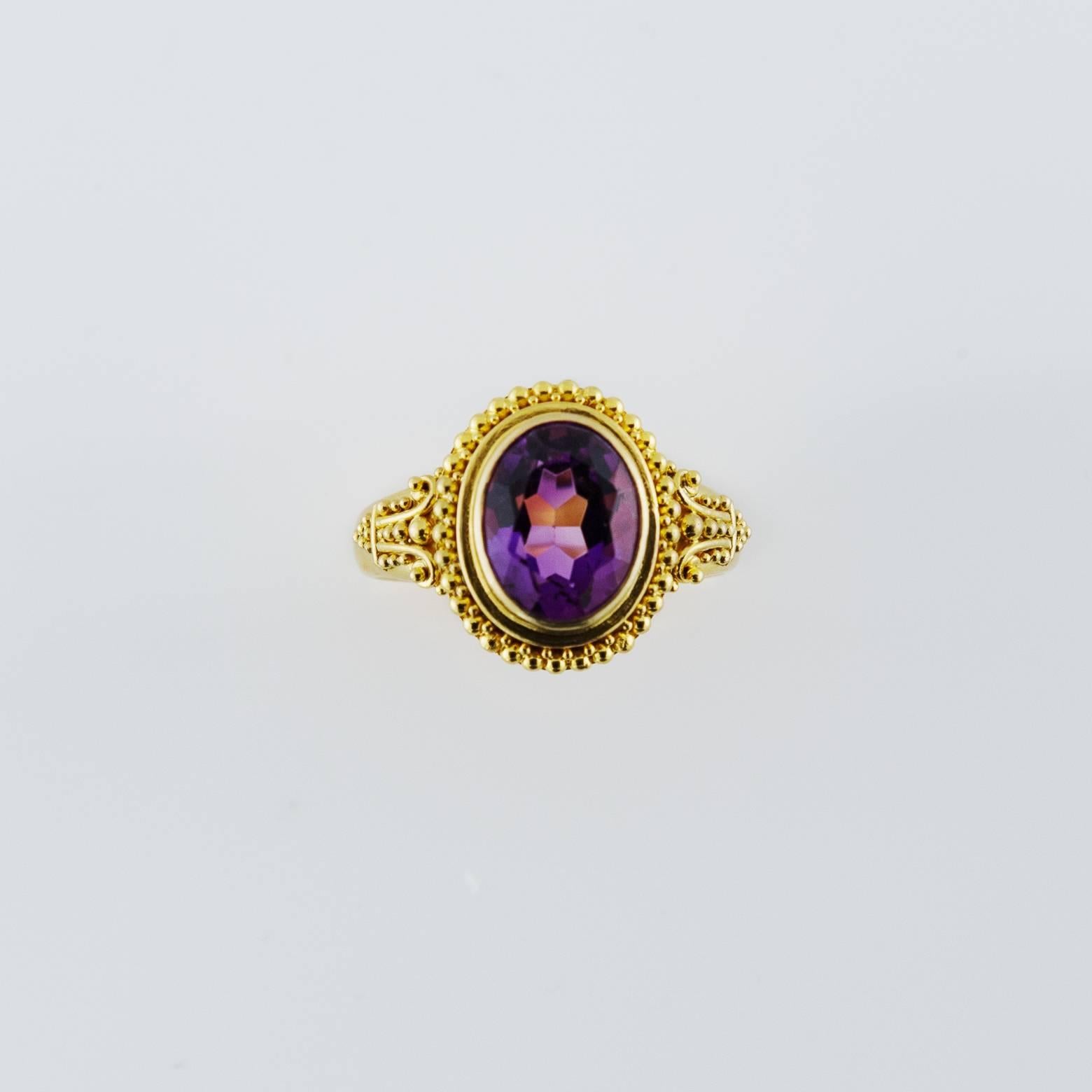 This dazzling bright amethyst ring is fit for royalty. The clarity of the amethyst is absolutely brilliant and reflects light in every direction. The texture of the bezel and design with the golden spheres looks as if it were taken from the