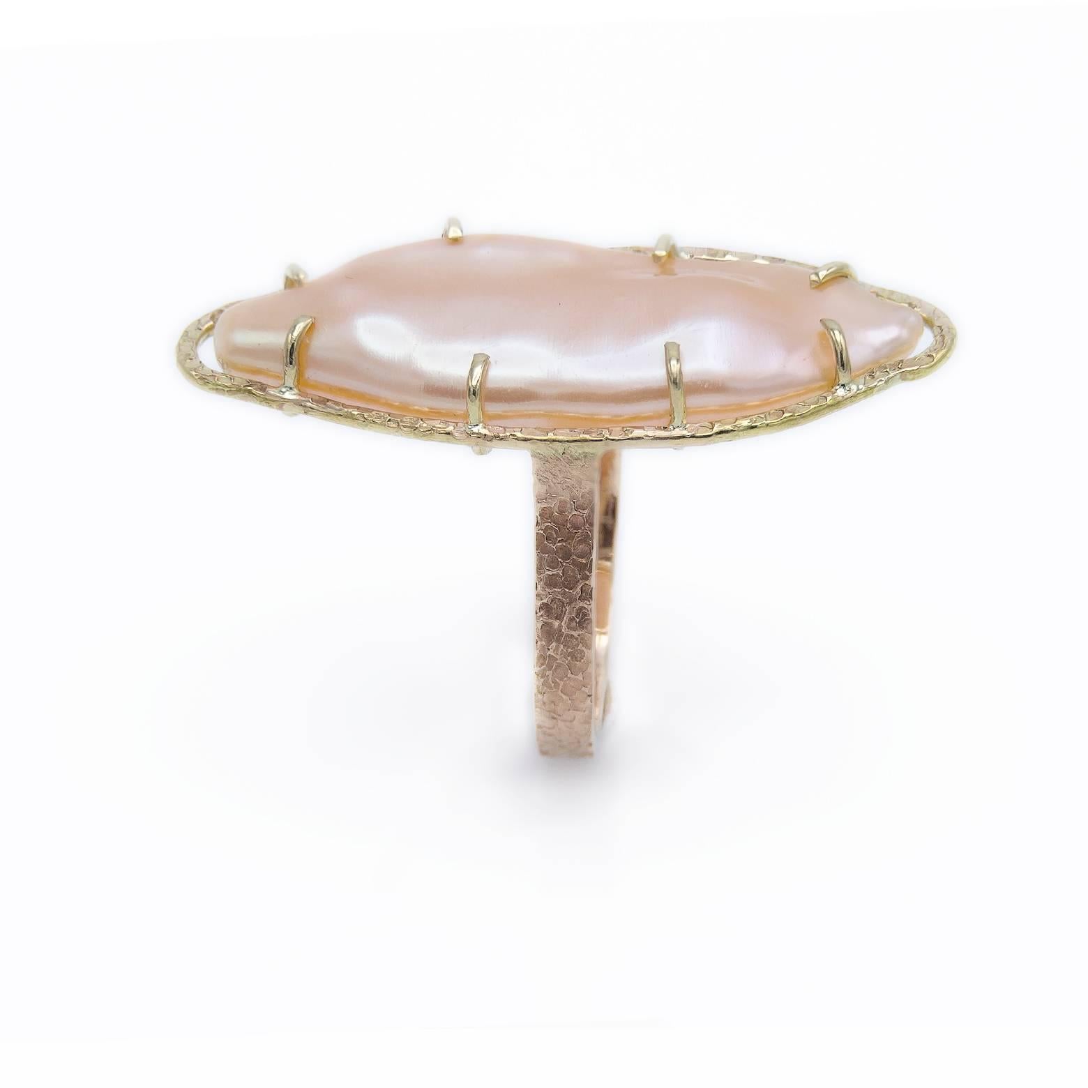 This luscious peach fresh water marquise-shaped pearl ring is glamorous and gorgeous. The creamy pearl is smooth with undulating round curves while the frame accents it's sheen with detailed texture. The bezel is in yellow gold and the band in a