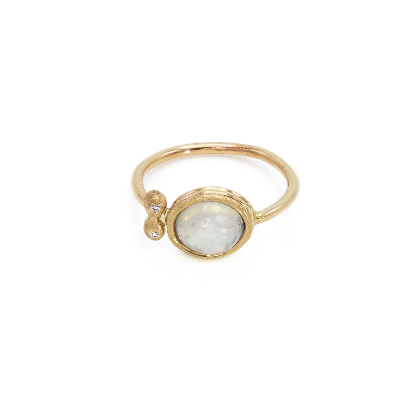 This gorgeous ring has a clear moonstone with the classic yet subtle rainbow shine and two round diamonds on the side. It's a fun and lighthearted piece of jewelry that is elegant with multiple textures on the 14K yellow gold and the two adorning