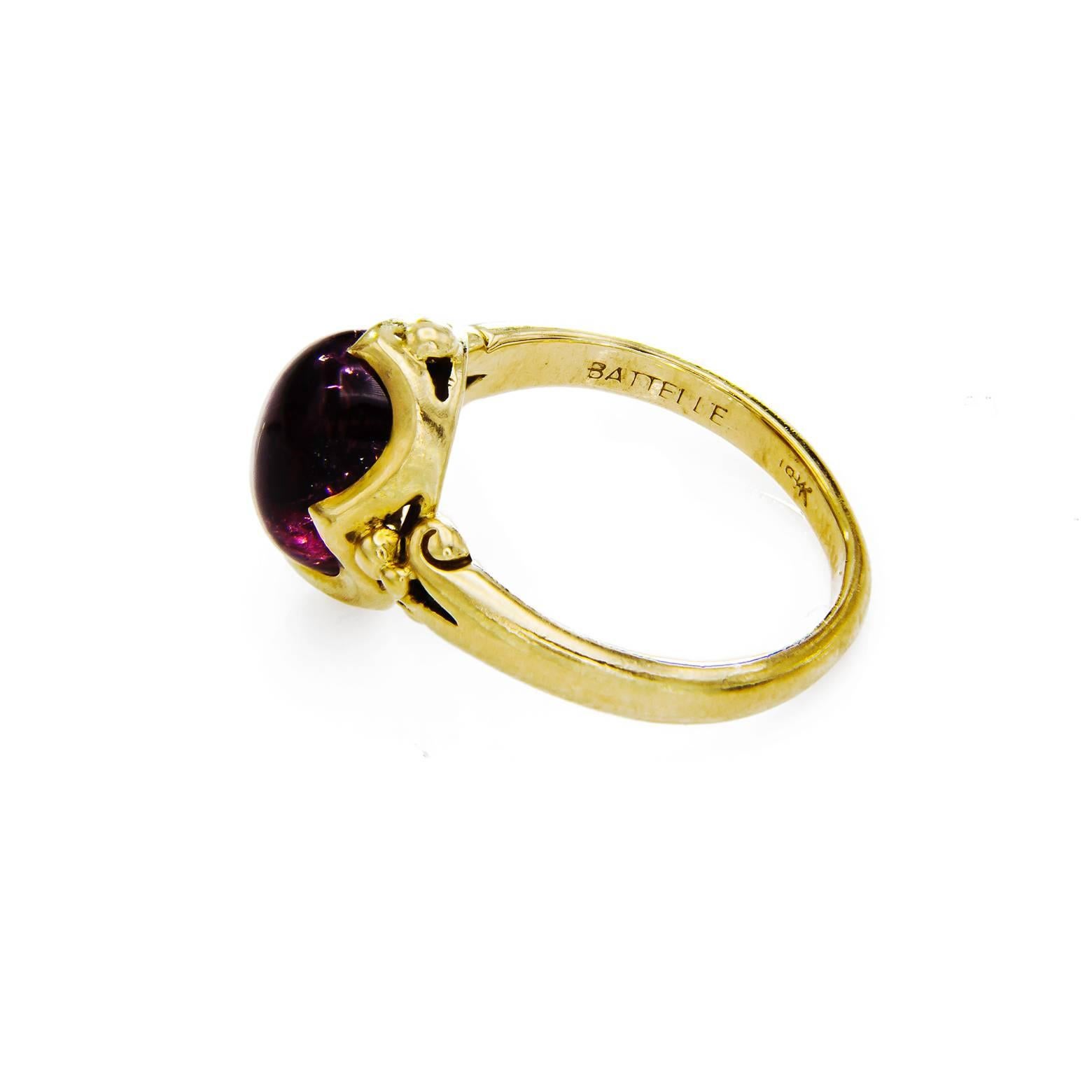 This ring is beautifully carved with a delicate sweeping design that cradles the tourmaline cabachon. The color of the stone is a deep claret red and the 18k yellow gold is a perfect compliment. The ring is a size 6 3/4. 