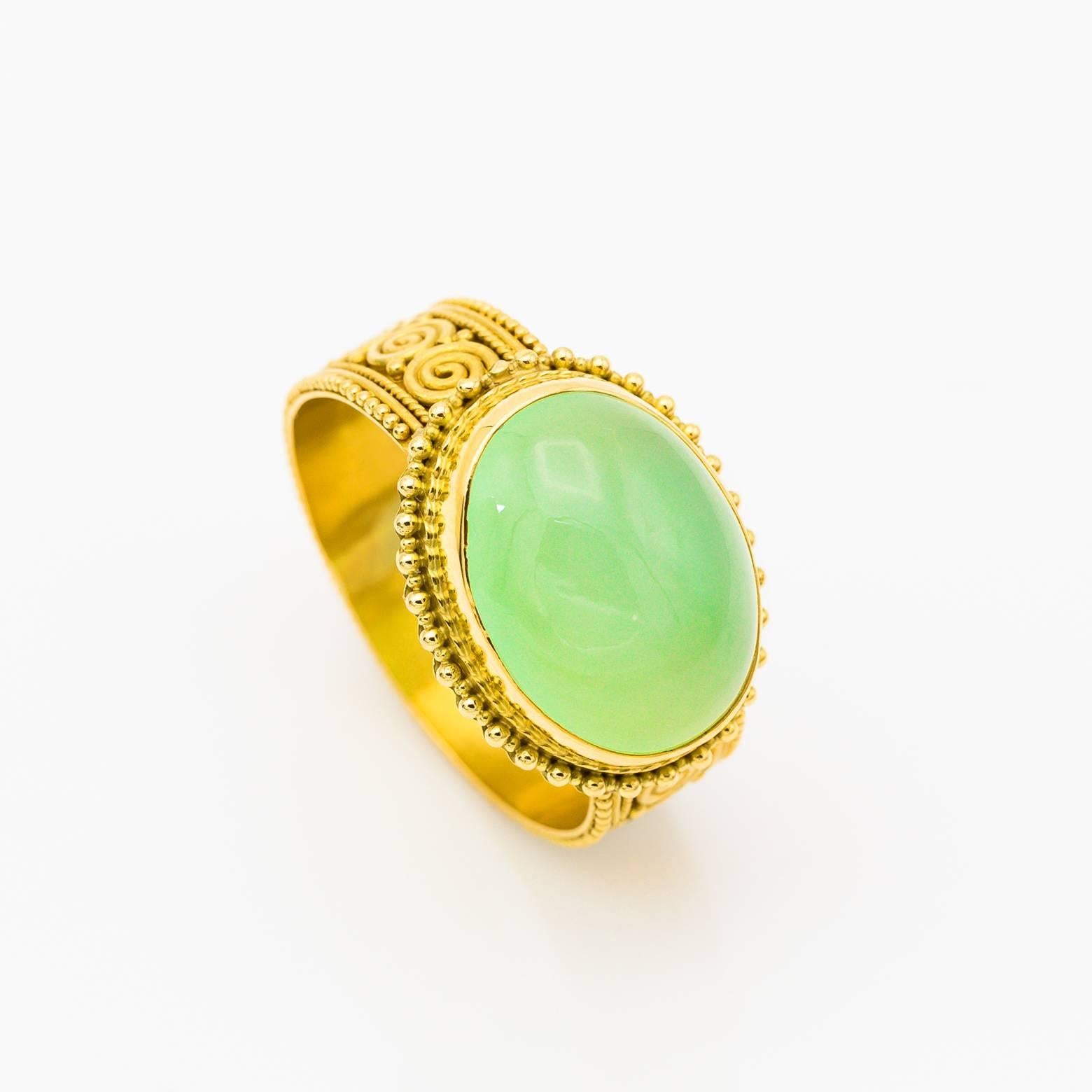 An oval Chalcedony is decorated in 22K yellow gold with intricate spiral detail handmade by one of our favorite designers. The bright yellow of the high carat gold glows with a creamy cloudy chalcedony in the middle. One of a kind and spectacular!