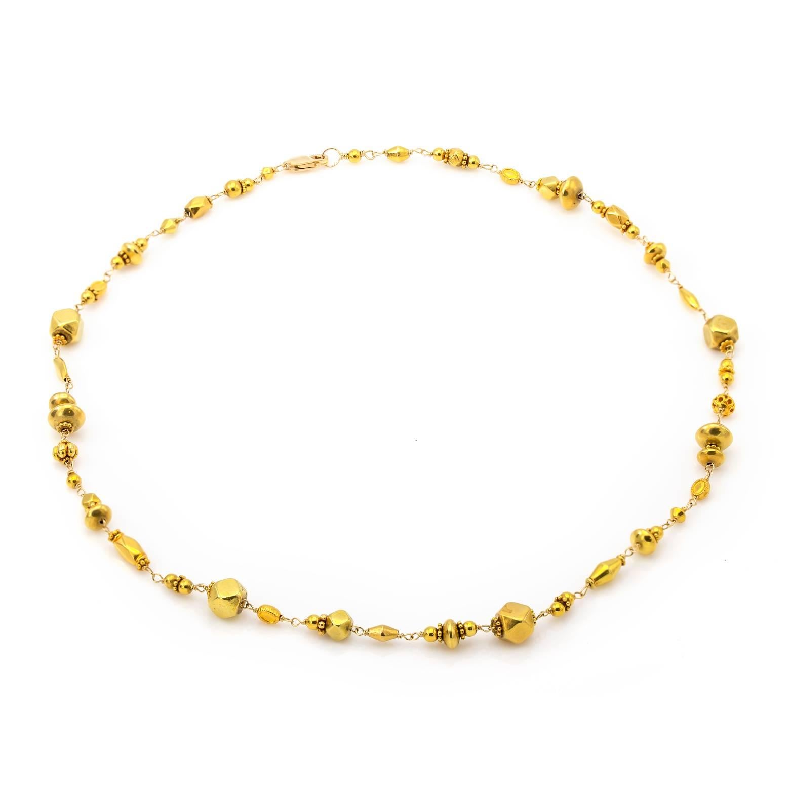 Many different shapes of gold beads spin and sparkle as they dance around a gold chain creating a unique blend that enriches everything around it. Deep 18K yellow gold dresses up everything adding glamour and style with a taste of Antiquity. 