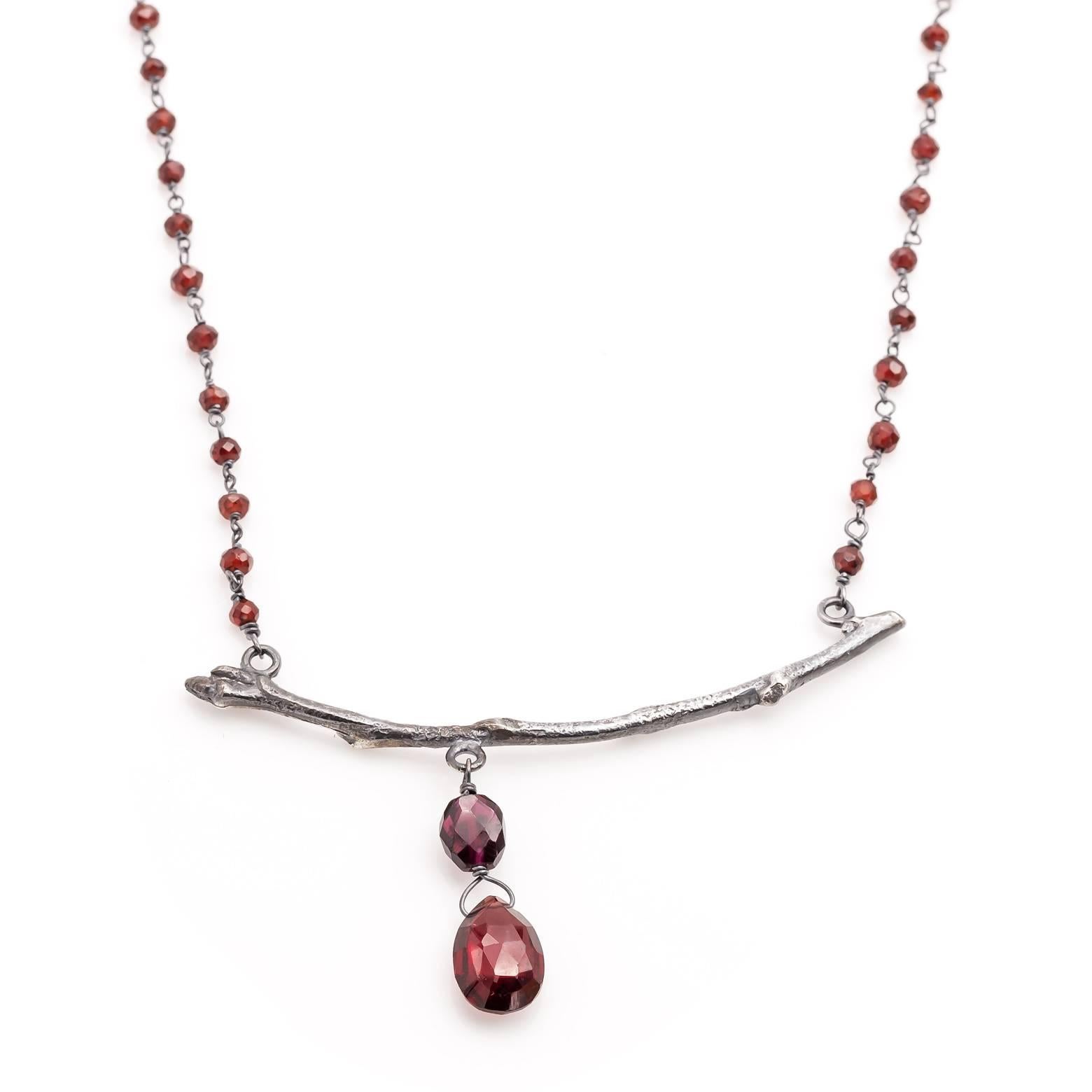 Oxidized sterling silver gives this cast branch a darker elegant look adorned with plentiful garnets. The lower dangling garnets are faceted and the faceted garnet beads along the dark silver chain create a delicacy that is also rich in color. Hand