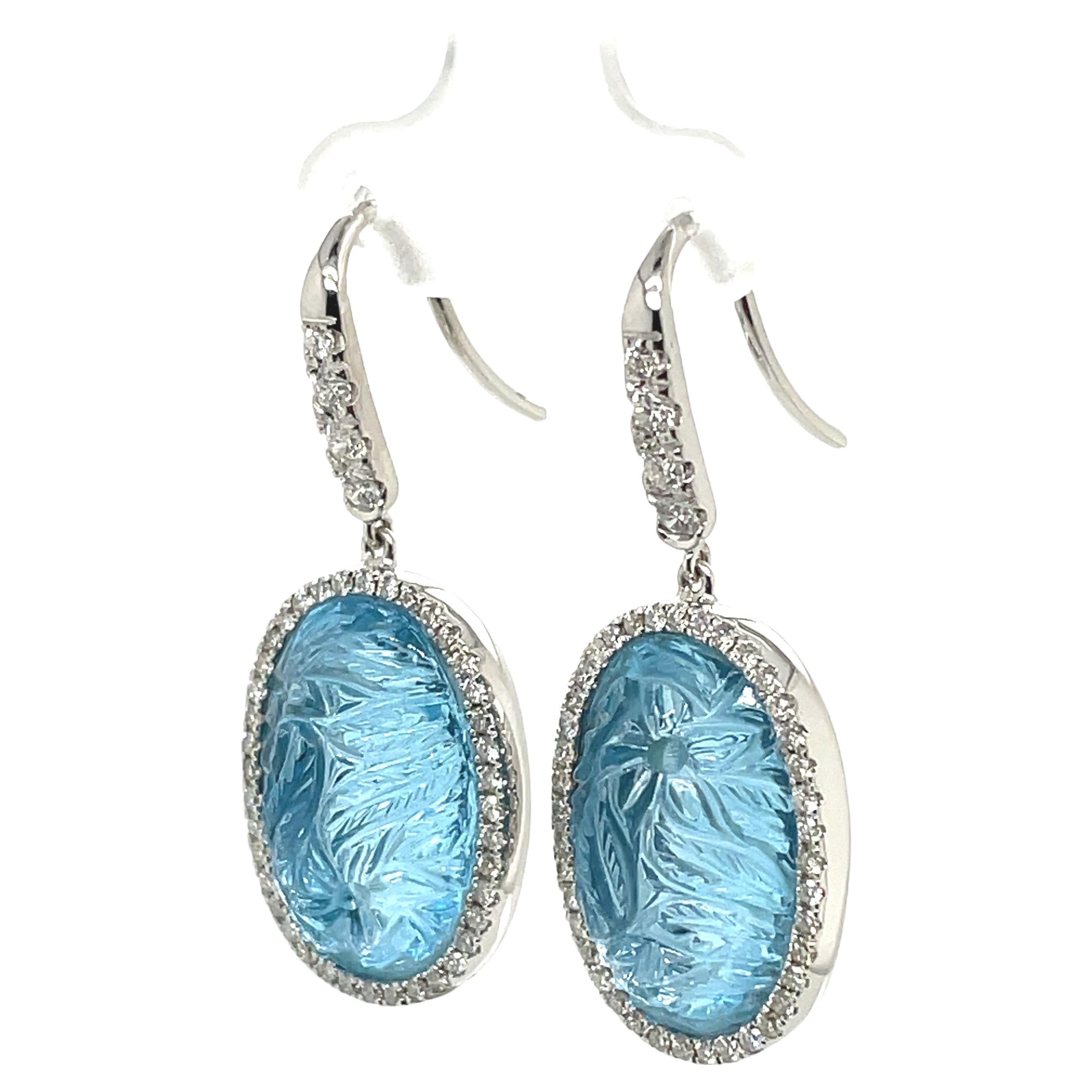 Explore the captivating color of this beautiful pair.

These earrings feature large blue topaz stones, totaling 27.41 cts. 

If you take a close look, you’ll notice that each blue topaz has intricate floral carvings.

Additionally, each earring is