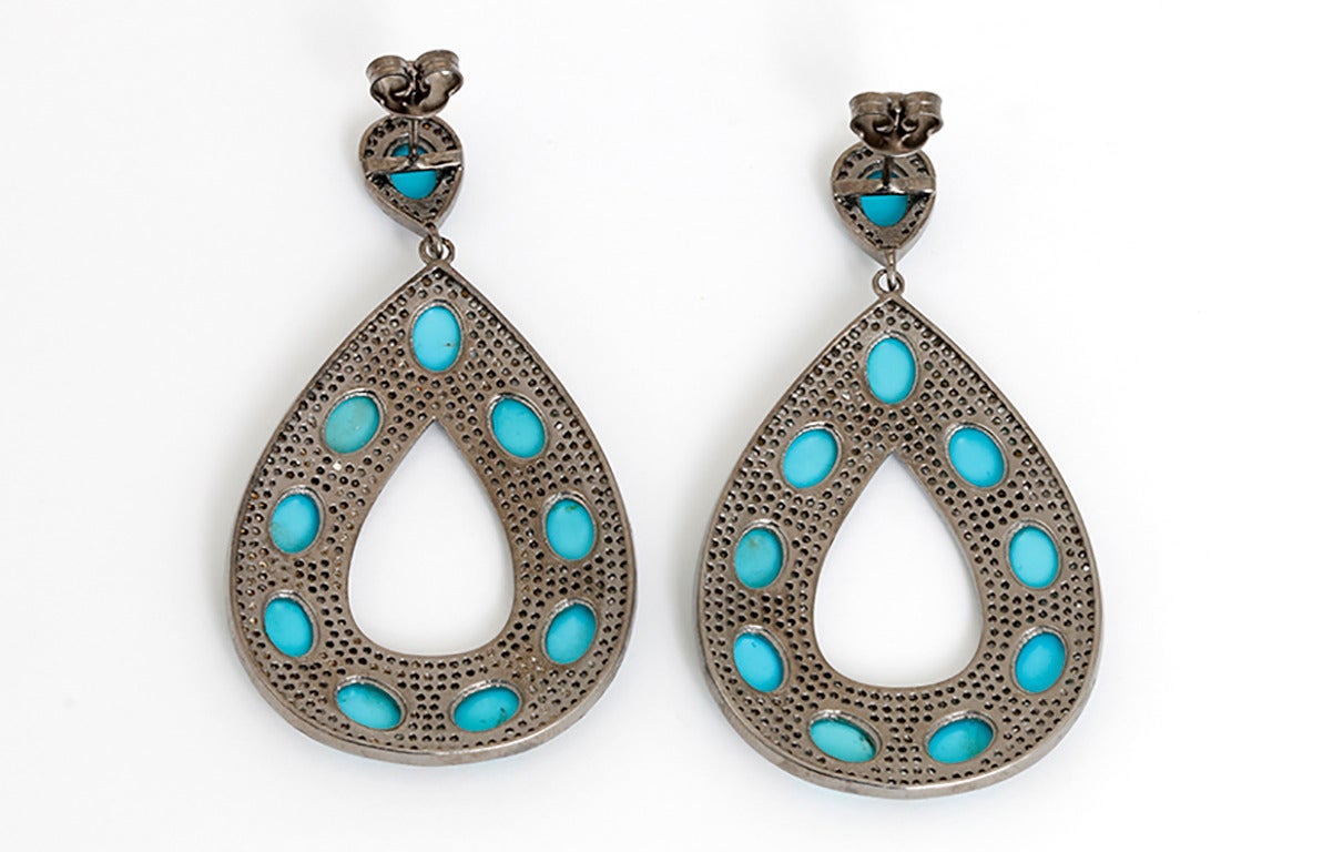 These amazing teardrop earrings each feature 10 turquoise stones surrounded by 5.56 carats of diamonds set in silver. The drop measures apx. 2-inches in length and apx. 1-1/2 inches in width at the widest. Total weight is 24.3 grams.