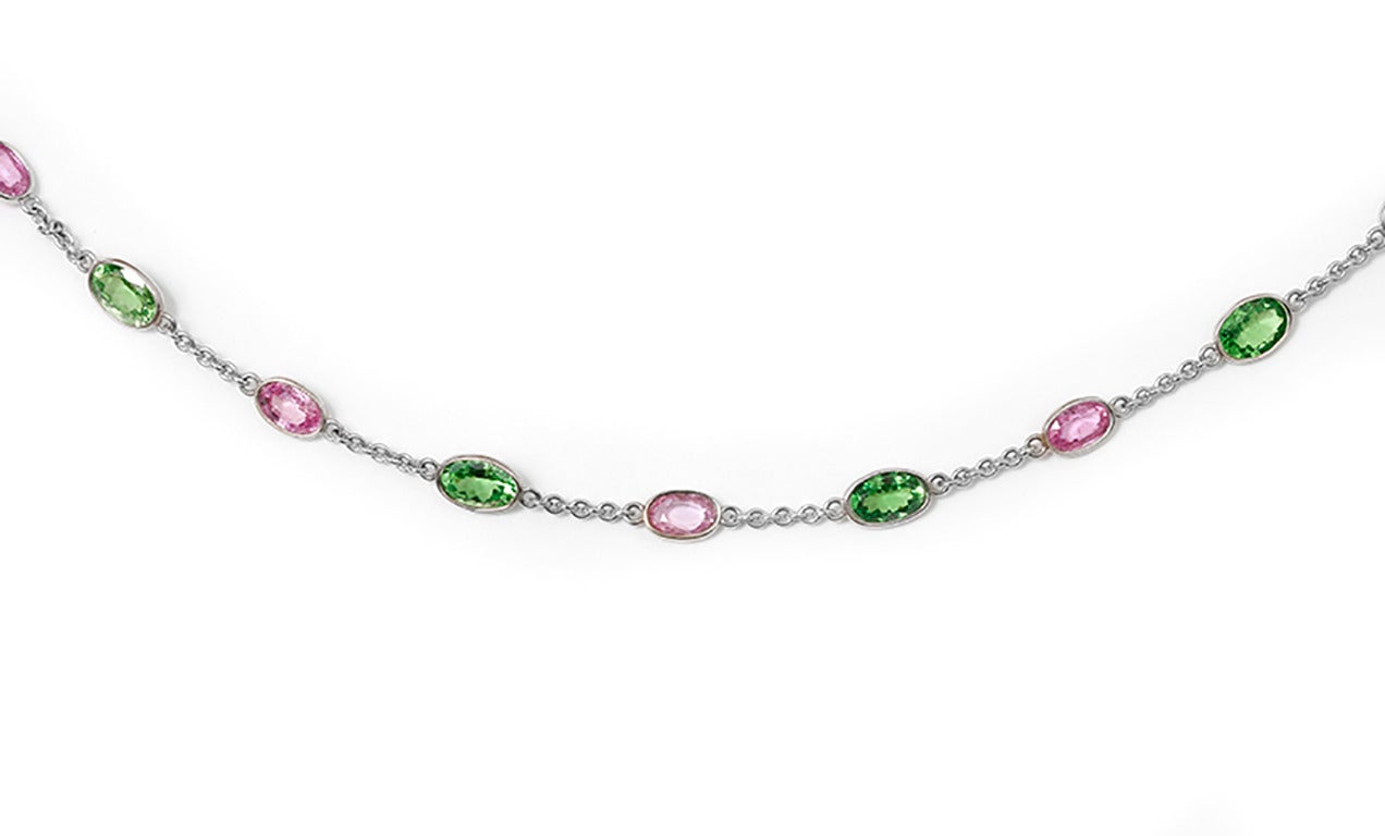 This chain necklace features pink sapphires and synthetic green spinels set in 18k white gold. The necklace measures apx. 33-inches in length. Total weight is 18.6 grams.